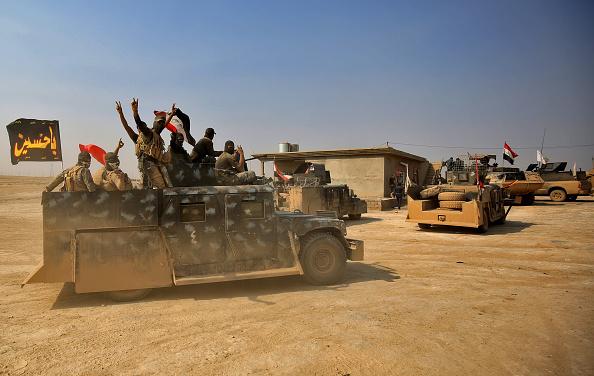 Pro-government Iraqi forces with a Shiite religious flag outside the village of al-Khuwayn, south of Mosul, last Sunday