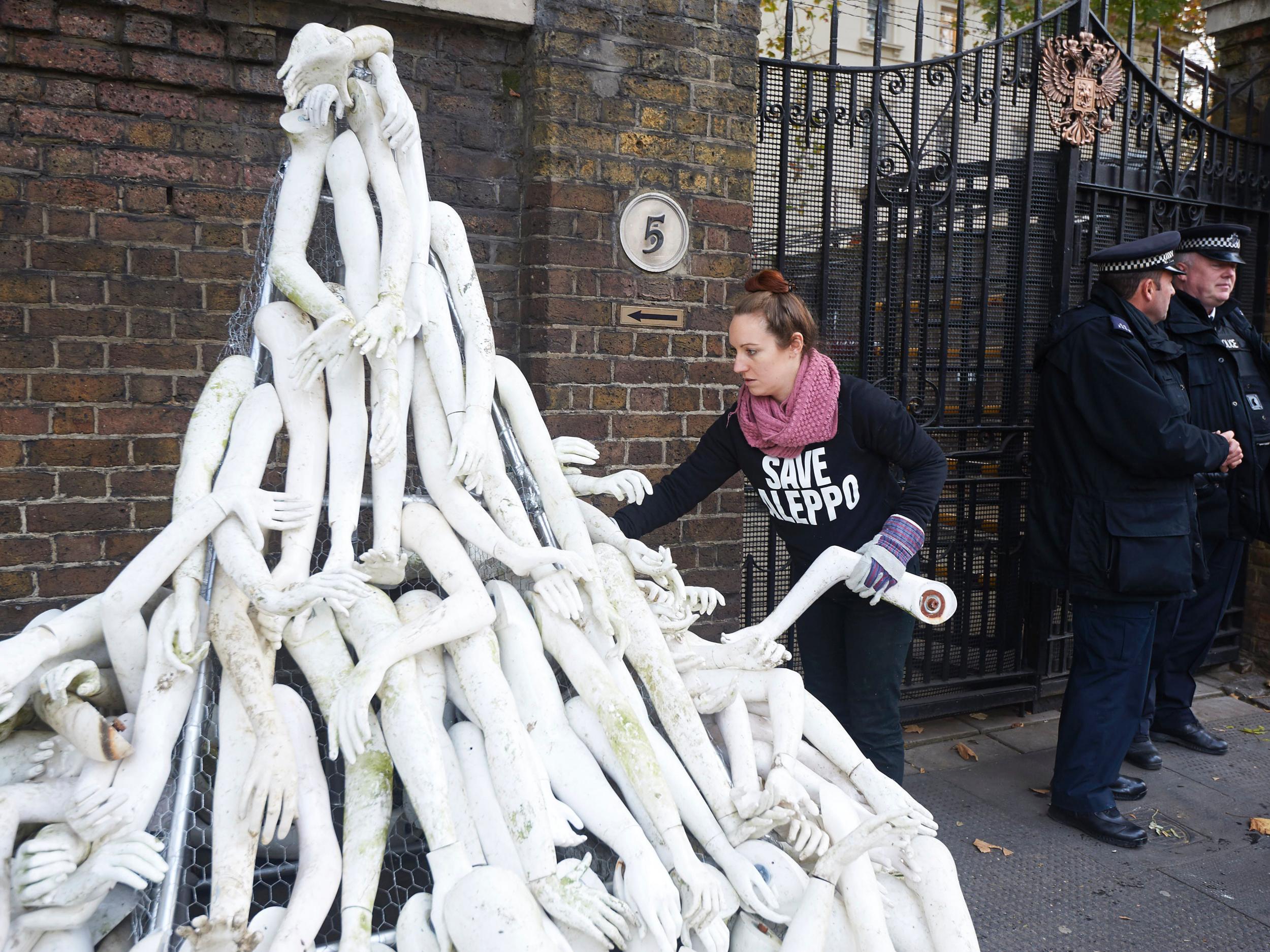 A campaigner creates a structure made from white mannequin limbs outside the Russian Embassy