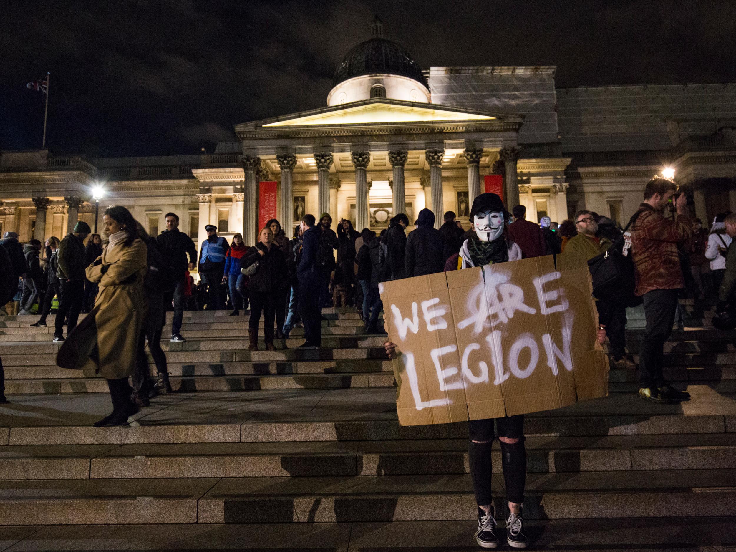 masked protester holds a sign which reads 'We Are Legion' in Trafalgar Square during the Million Mask March on November 5, 2016 in London