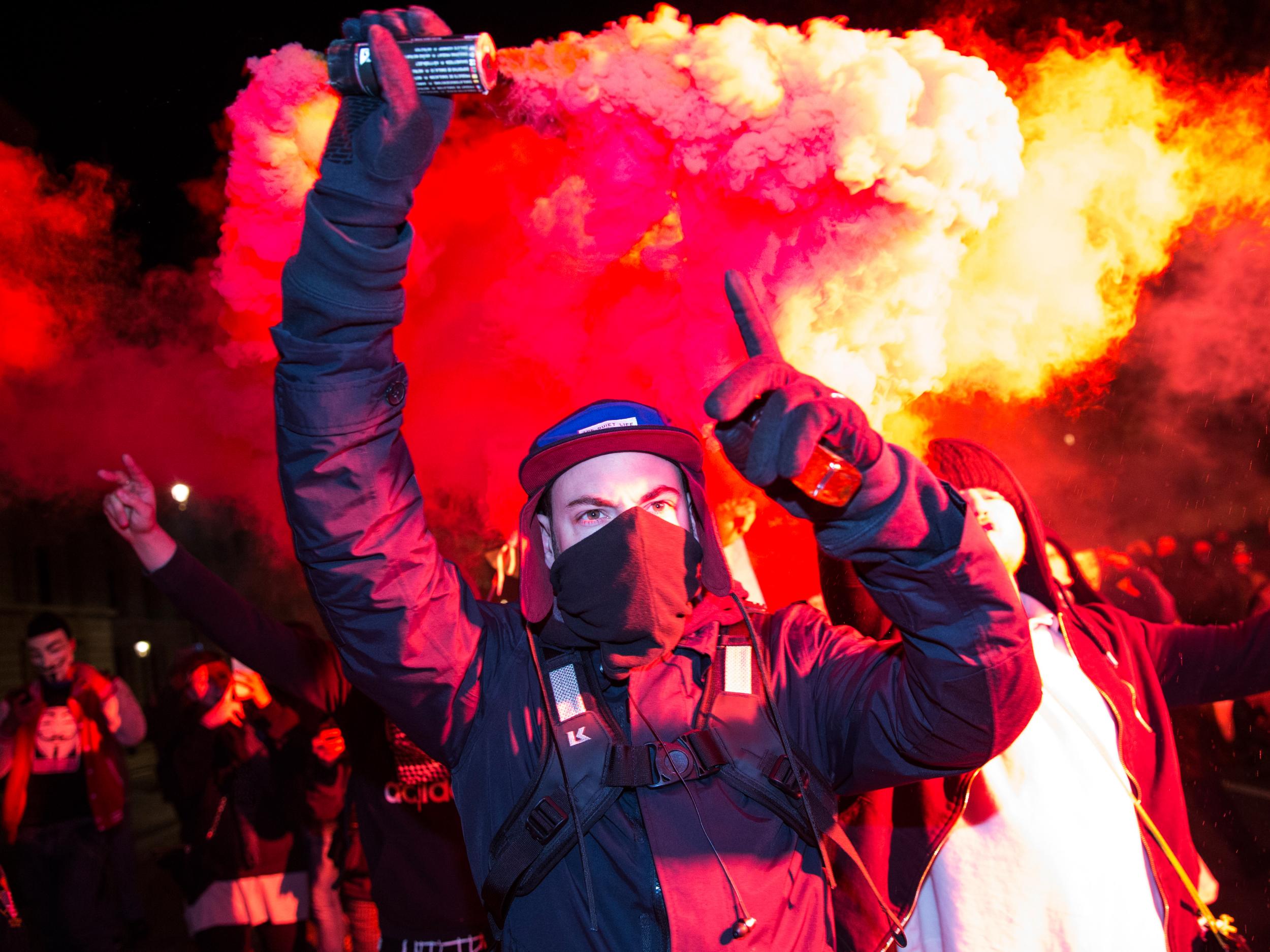 A protestor brandishes a flare in Whitehall on the Million Mask March on Saturday night