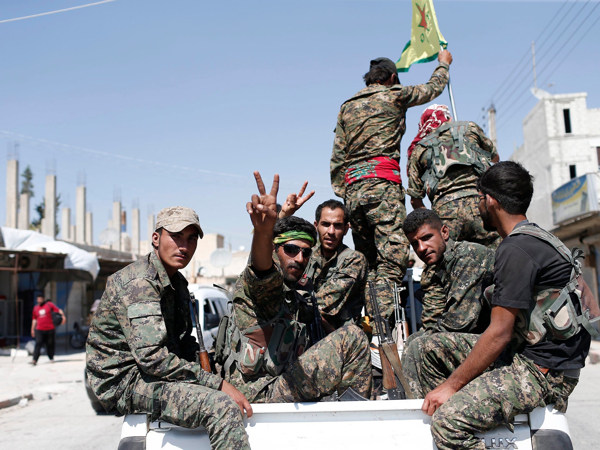 Members of the Kurdish People's Defence Units (YPG), part of the umbrella Syrian Democratic Forces (SDF), flash the victory sign after a Raqqa sortie in 2015