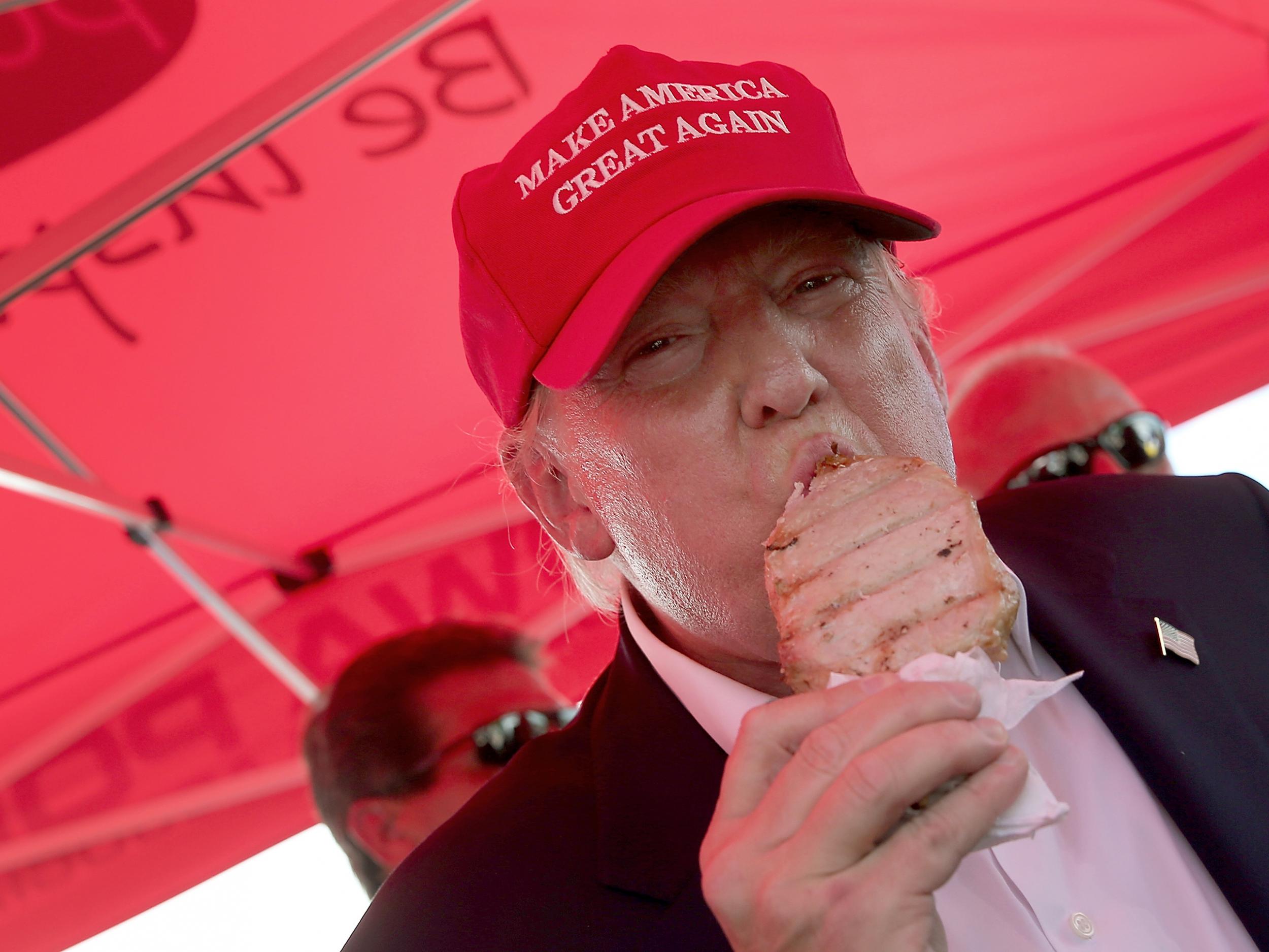 Republican presidential candidate Donald Trump eats a pork chop on a stick and gives a thumbs up sign to fairgoers at the Iowa State Fair