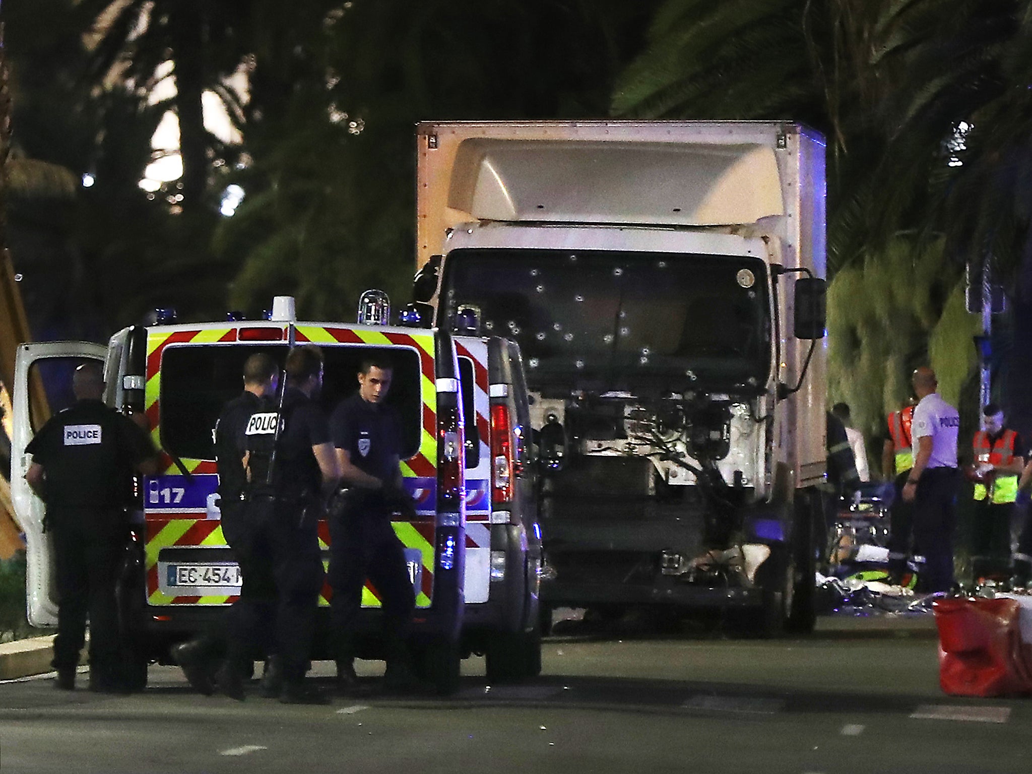 Police officers and rescue workers stand near a van that ploughed into a crowd leaving a fireworks display in the French Riviera town of Nice