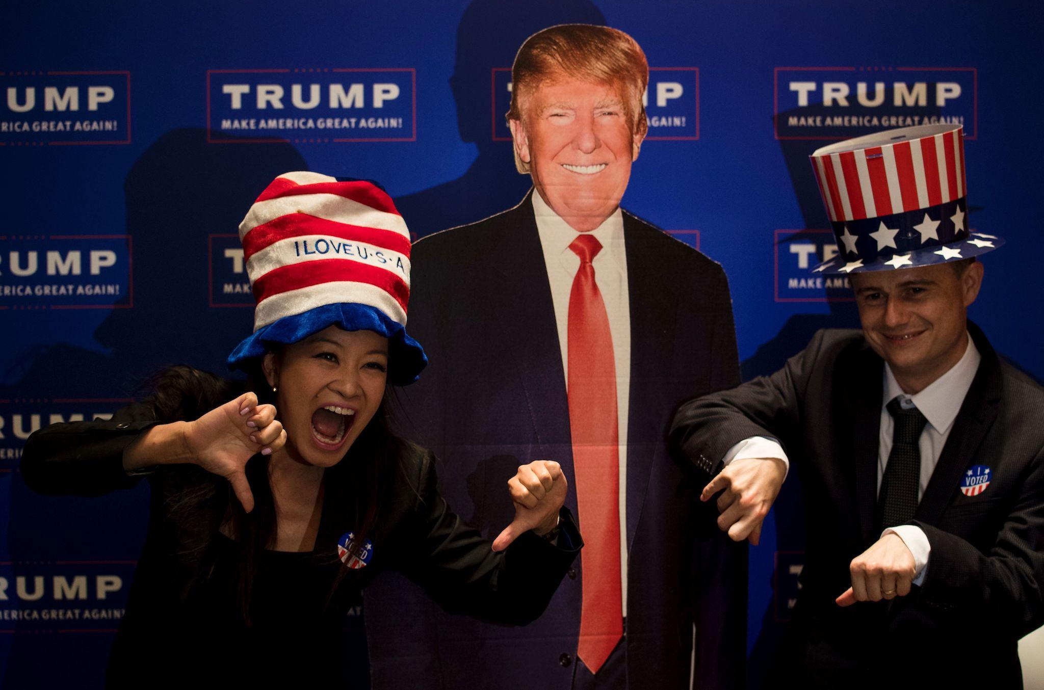 A couple poses for a picture next to a cardboard cut outs of US presidential candidat Donald Trump during an election event organised by the US consulate in Shanghai on November 9, 2016