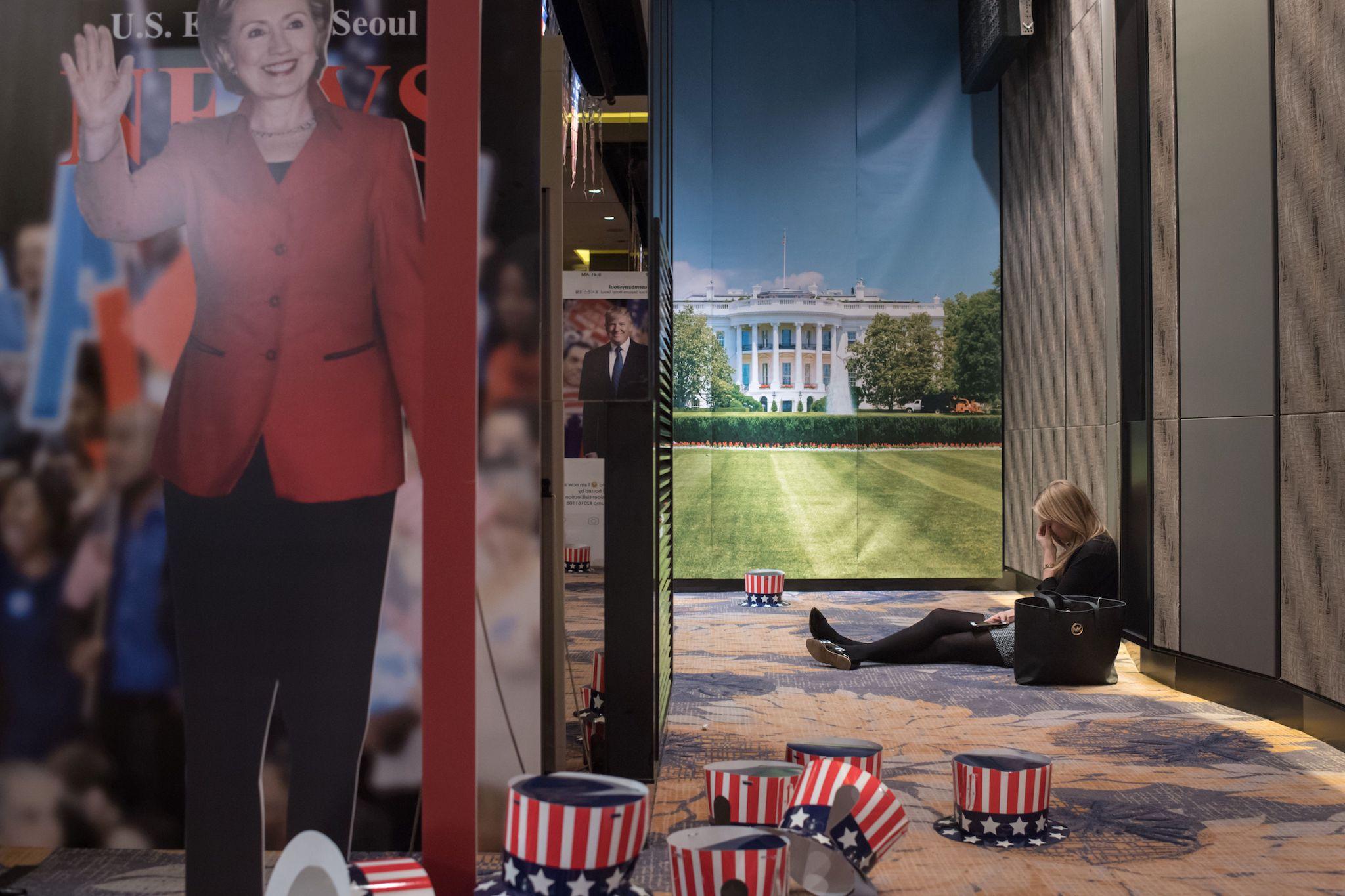 A woman sits on the floor behind a cut-outs of US presidential nominees Hillary Clinton and Donald Trump at an election event organised by the US embassy, at a hotel in Seoul on November 9, 2016 ED JONES/AFP/Getty Images