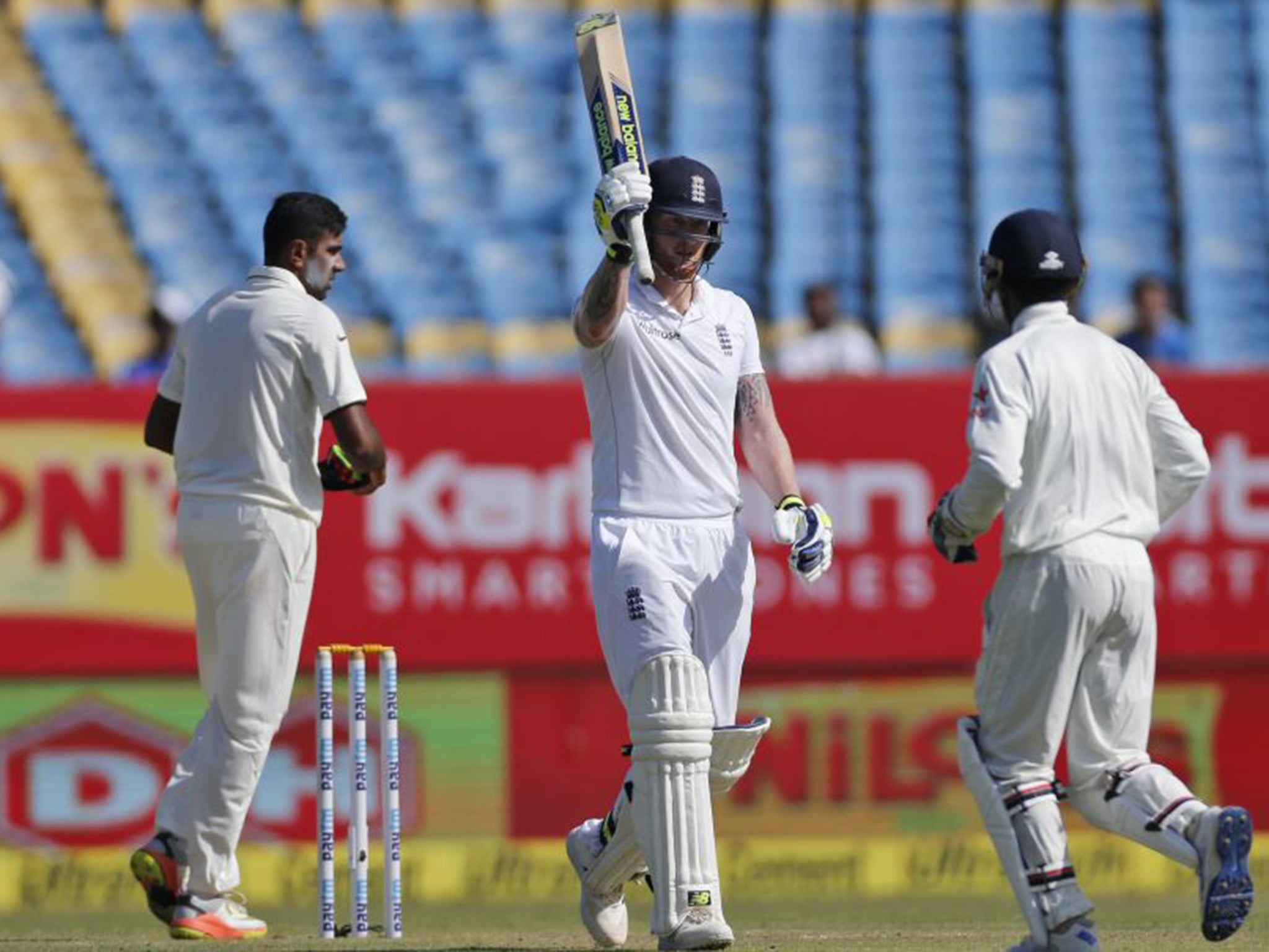 Stokes raises his bat after reaching his century in Rajkot