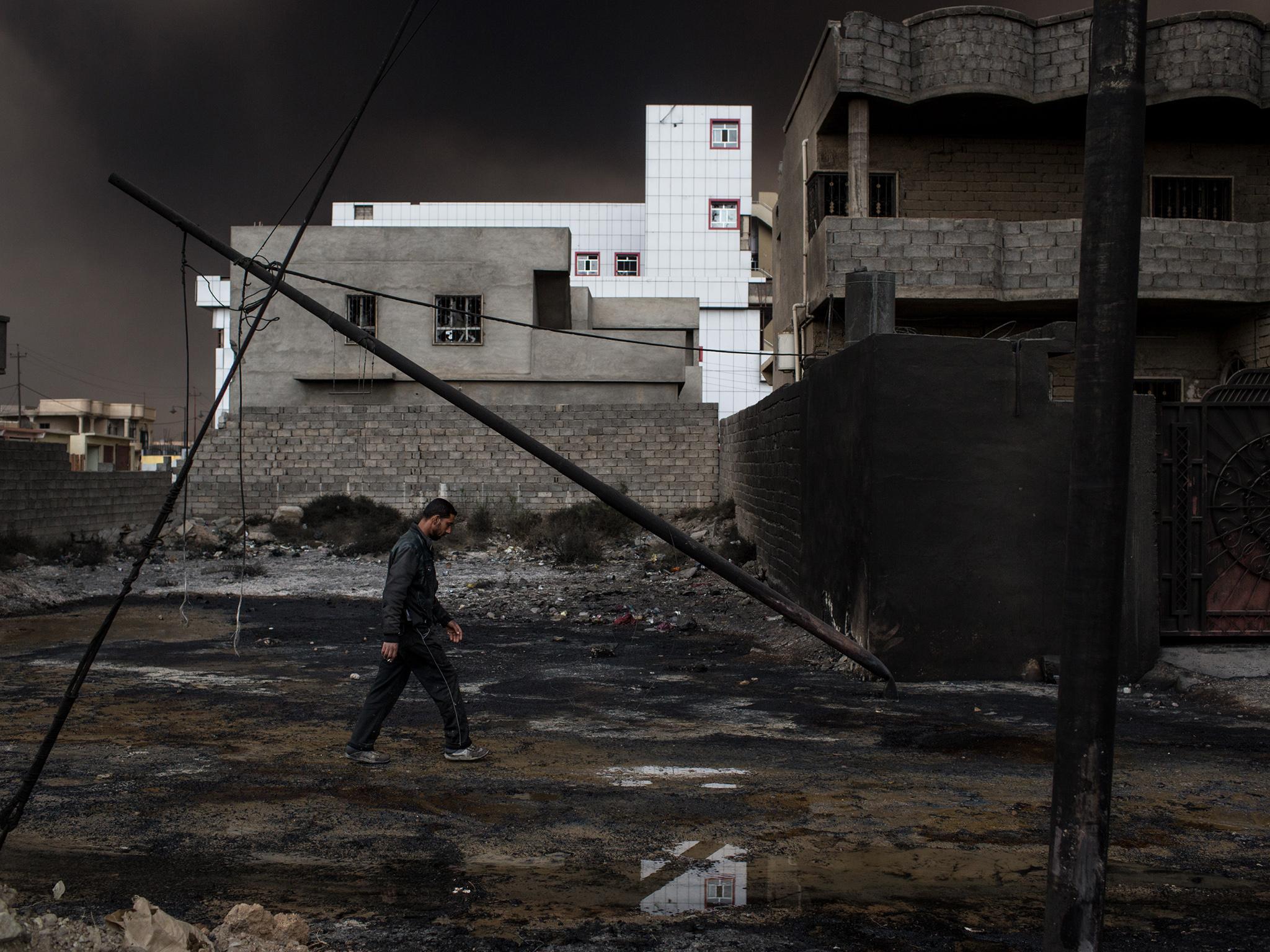 A man strolls through a derelict street but it's hard to tell what time of day it is