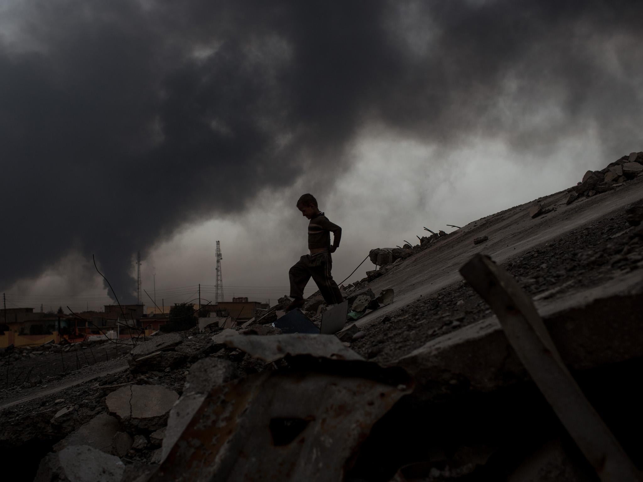 A young boy plays on rubble at a destroyed football stadium