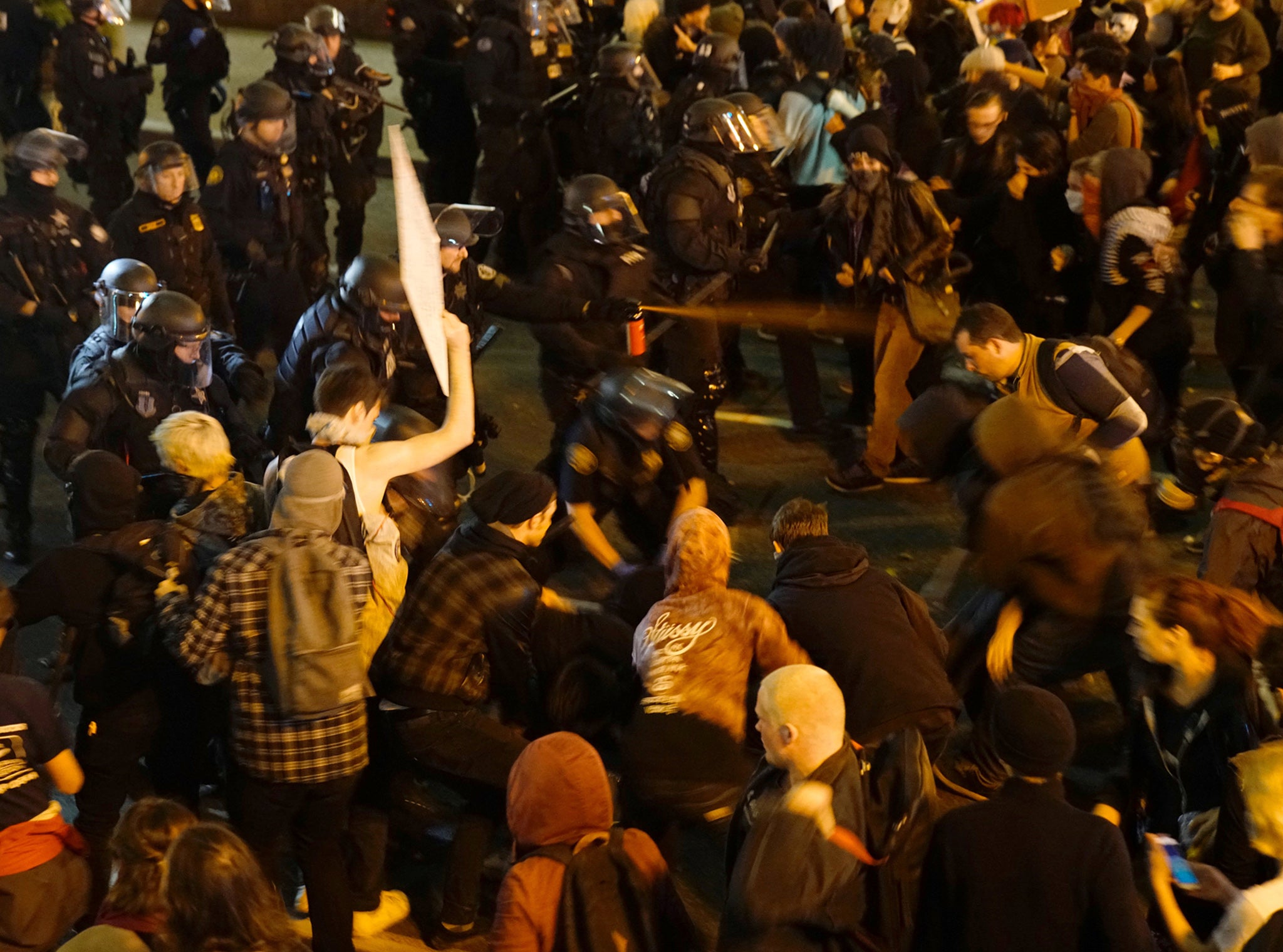 A police officer sprays the crowd with an irritant during a protest against the election of Donald Trump as US President in Portland, Oregon