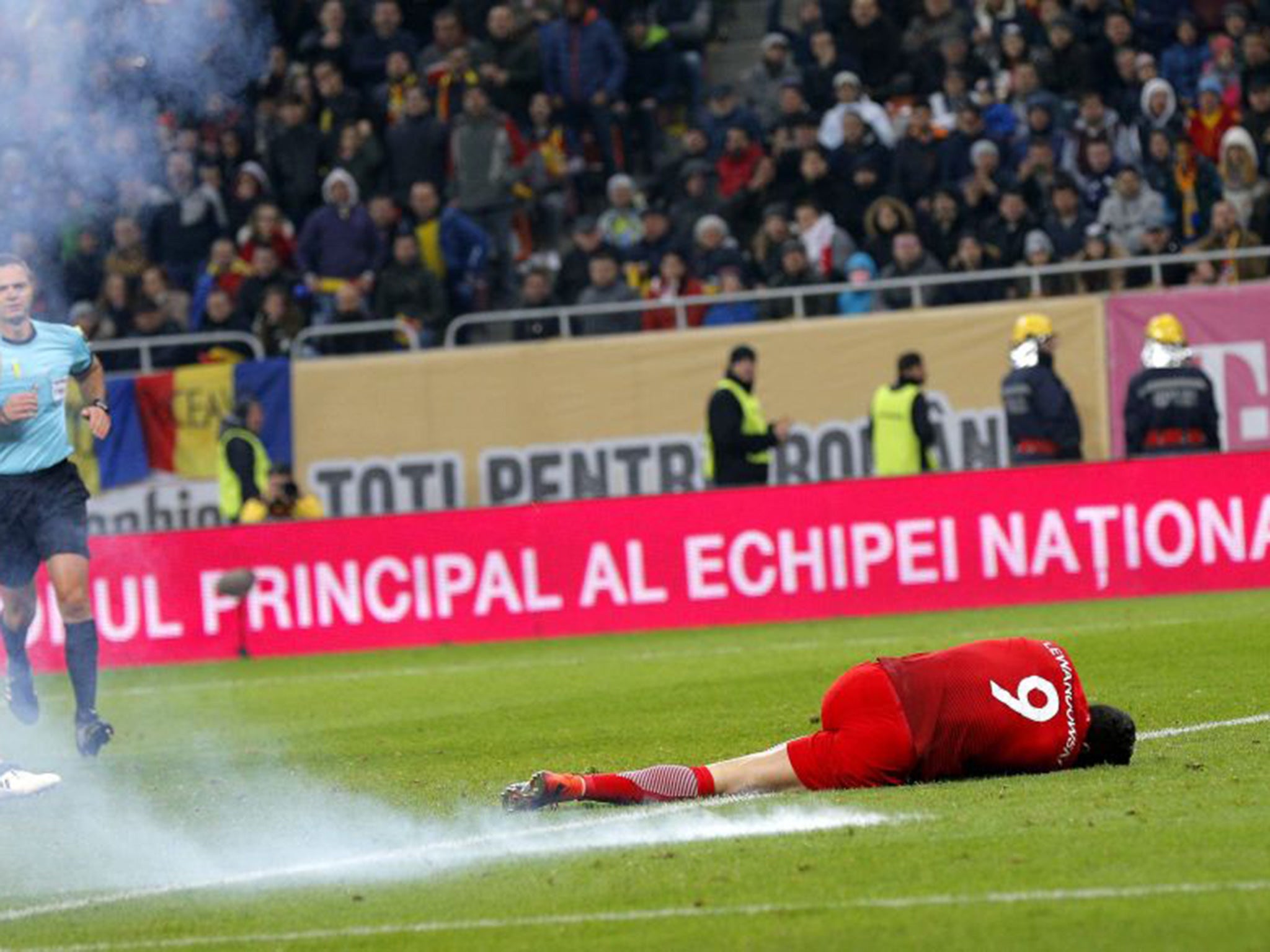 Lewandowski lies on the turf after a nearby flare explodes