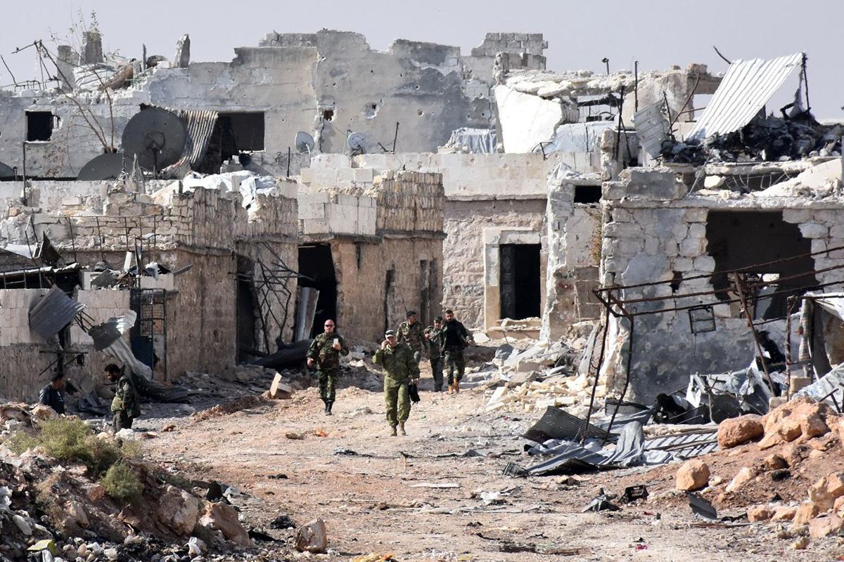 Syrian pro-government forces walk around in the village of Minyan, west of Aleppo, after they retook the area from rebel fighters on November 12, 2016.