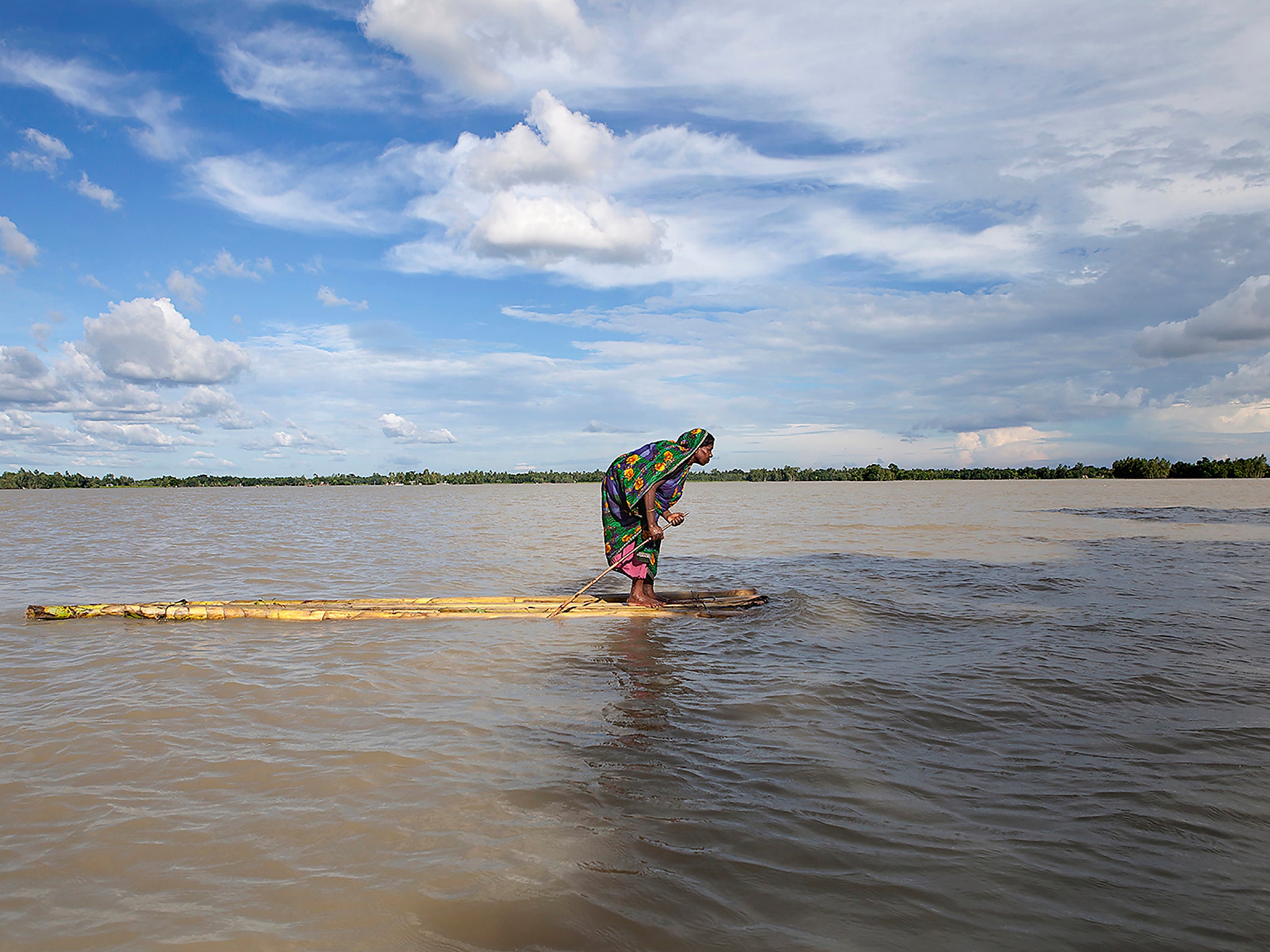 A woman caught in a flood in Bangladesh seeks dry ground