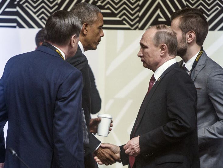 US President Barack Obama, behind left, shakes hands with Russia's President Vladimir Putin