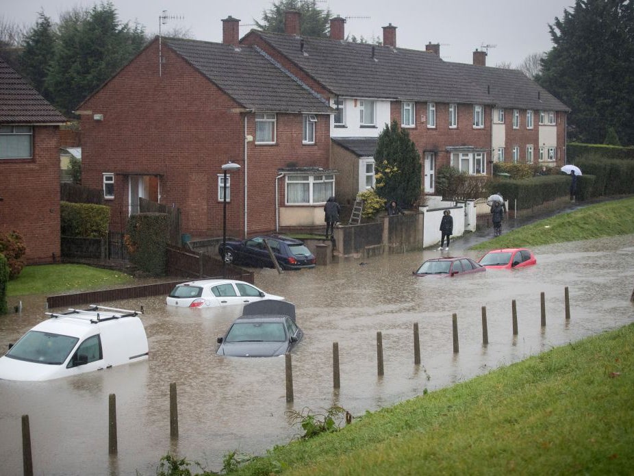 Residents look at cars that have been submerged under several feet of flood water in Hartcliffe, Bristol