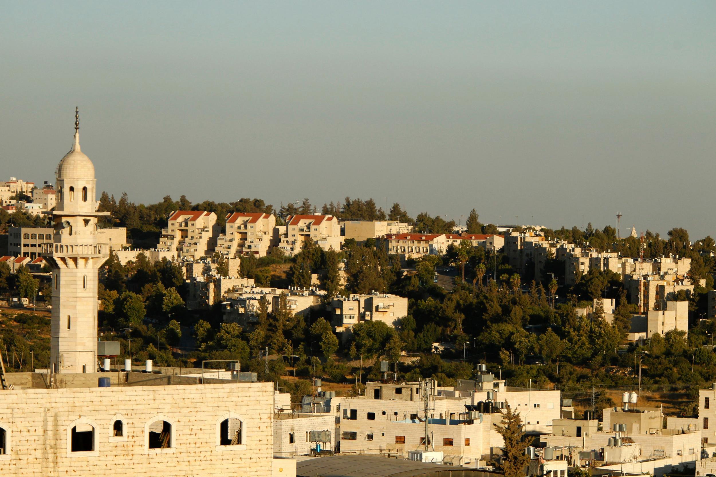 A picture taken from the West Bank city of Hebron on July 6, 2016 shows a mosque in front of buildings in the Kiryat Arba Jewish settlement on the outskirts of the Palestinian flashpoint city.