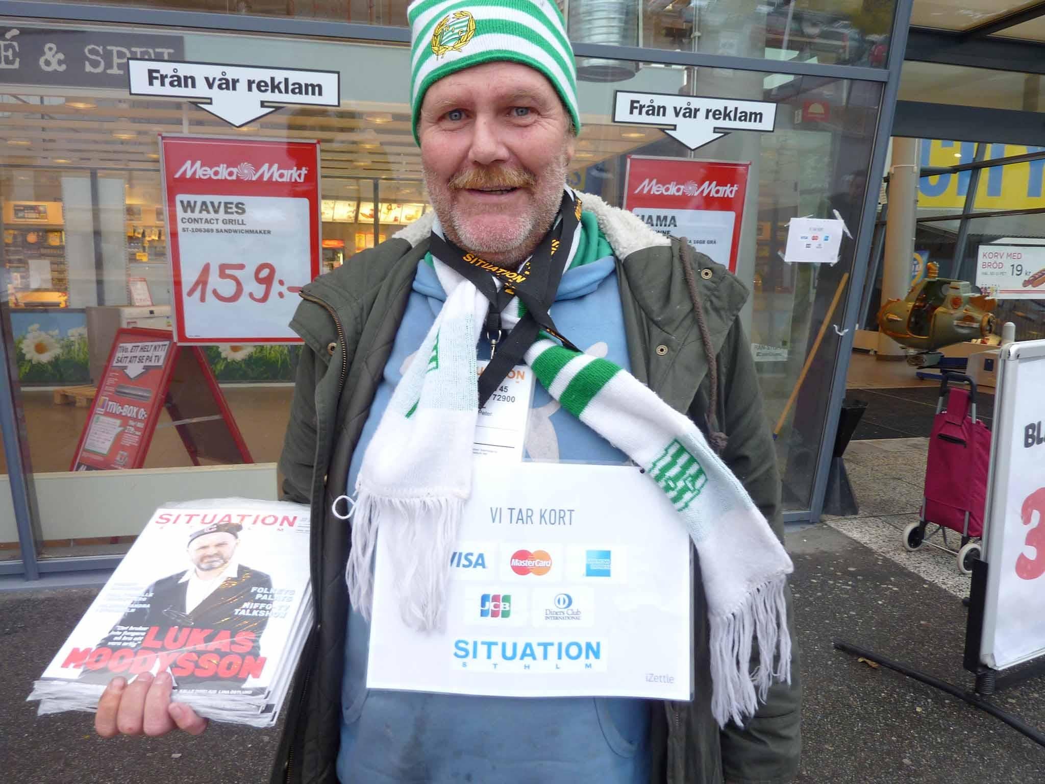 A vendor sells Stockholm's street paper for the homeless wears a sign reading 'we take cards