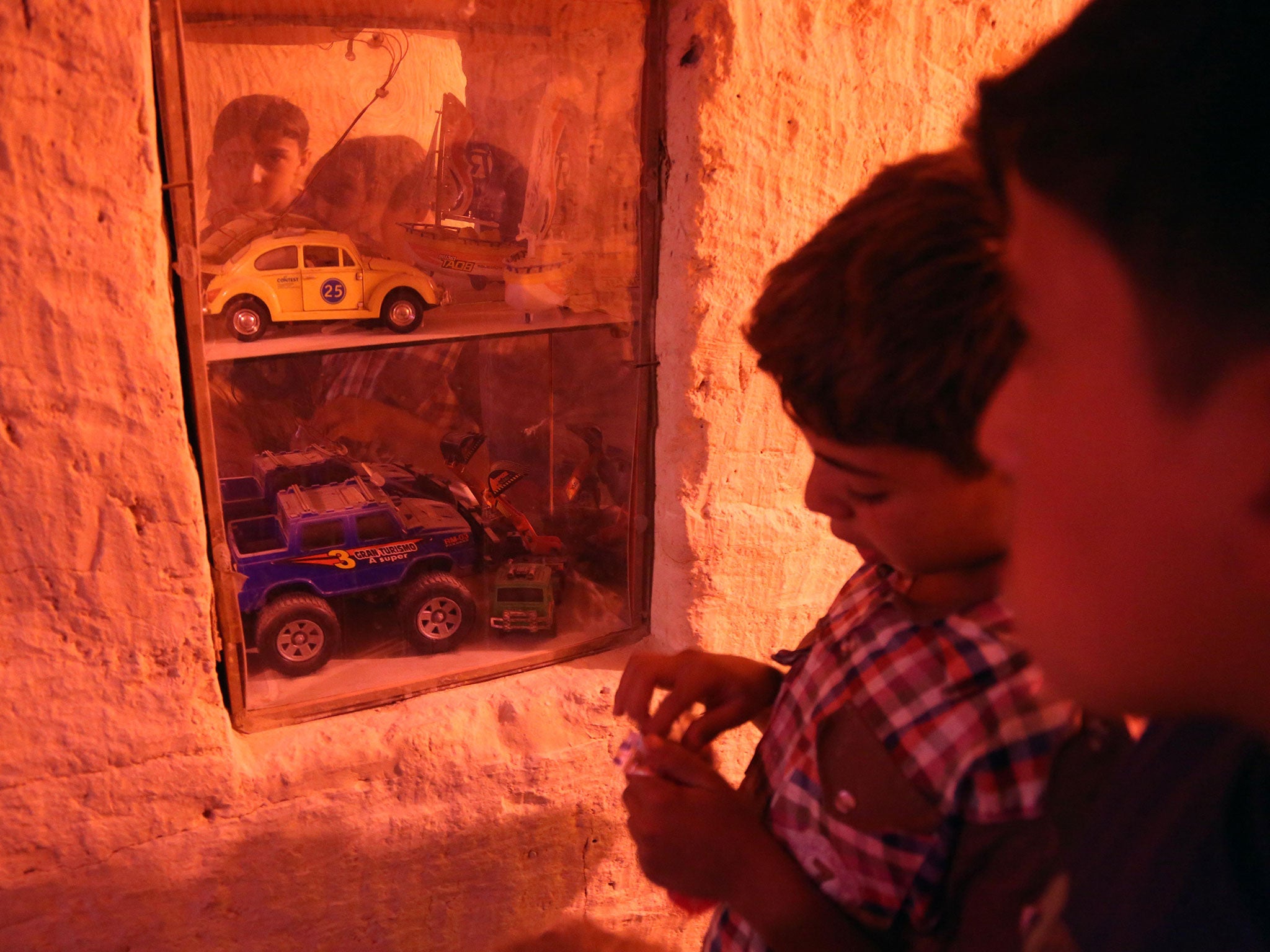 Boys look through a show window inside the tunnel that provides a safe passage for children between the two basements that form the 'Land of Childhood' in a besieged town in Syria