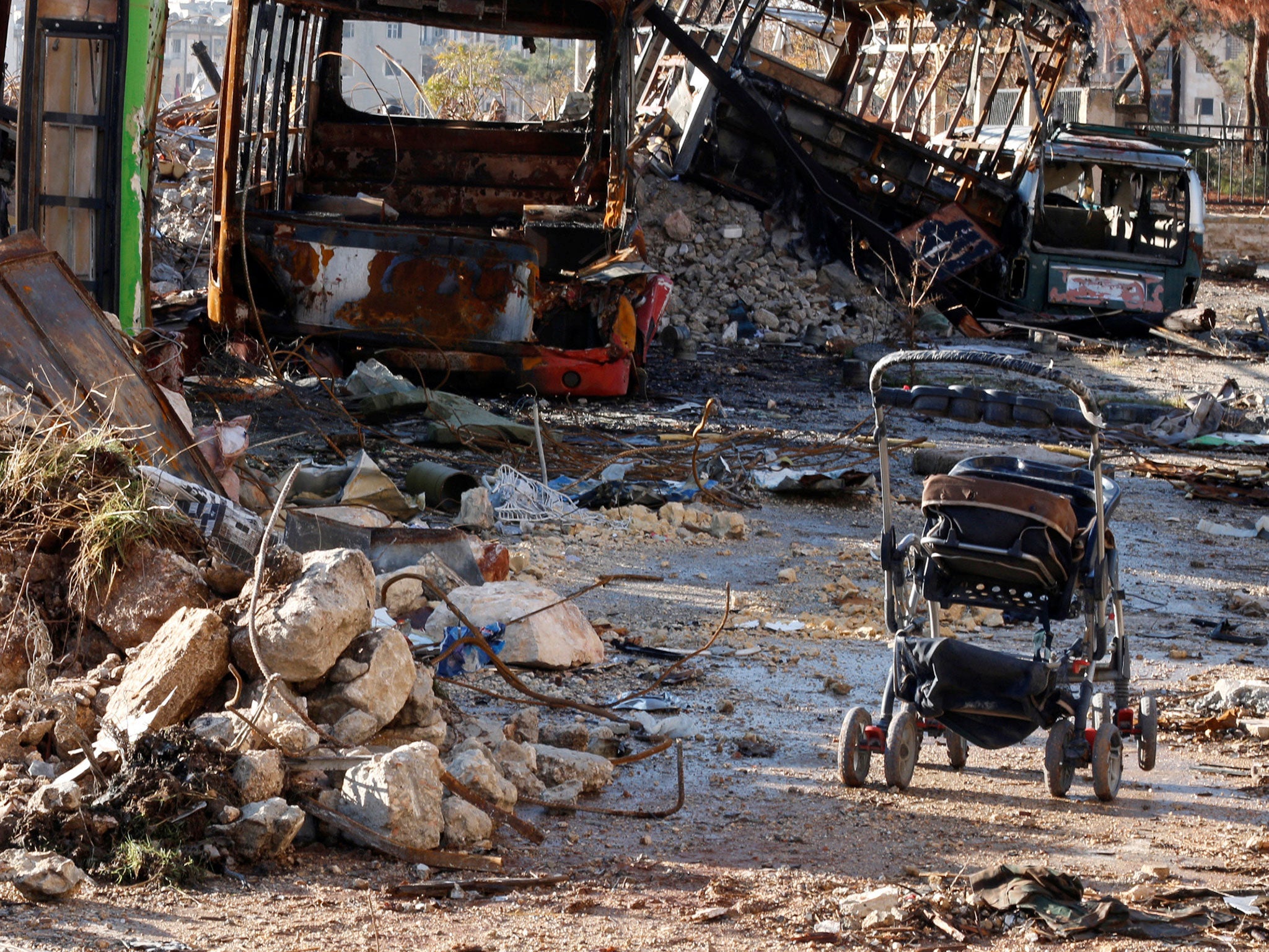 An abandoned pushchair near destroyed vehicles used as barricades by rebels in Hanano, Aleppo, on 2 December