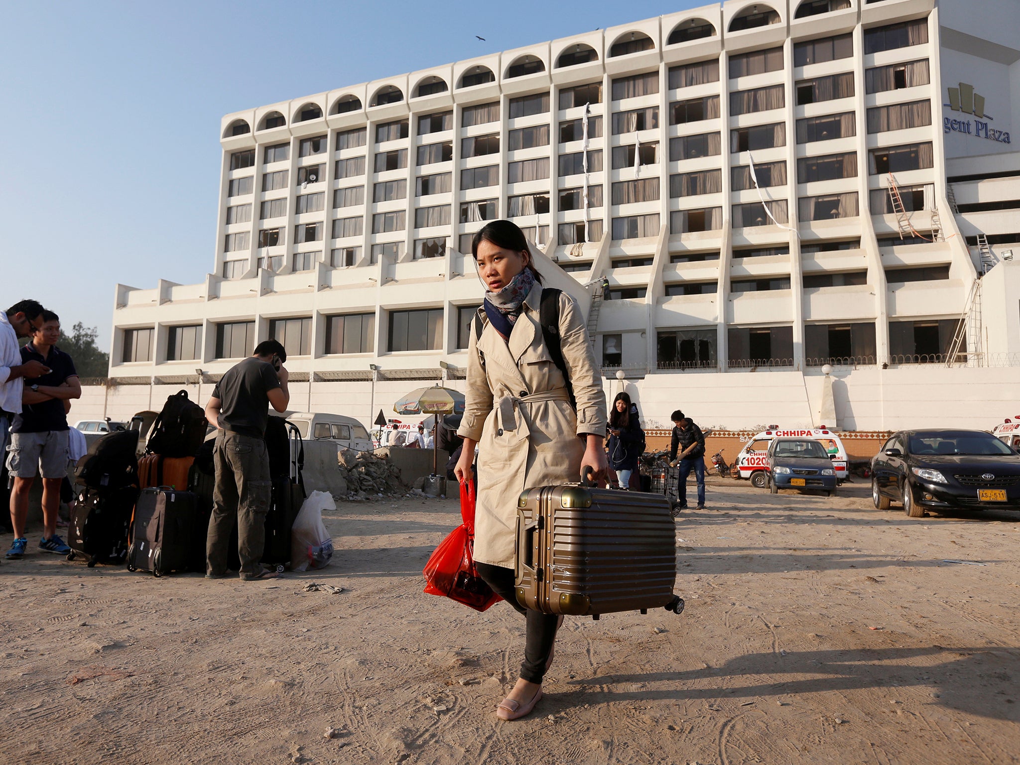 A foreign guest carrying her belongings as she leaves after a fire erupted in a hotel early morning in Karachi