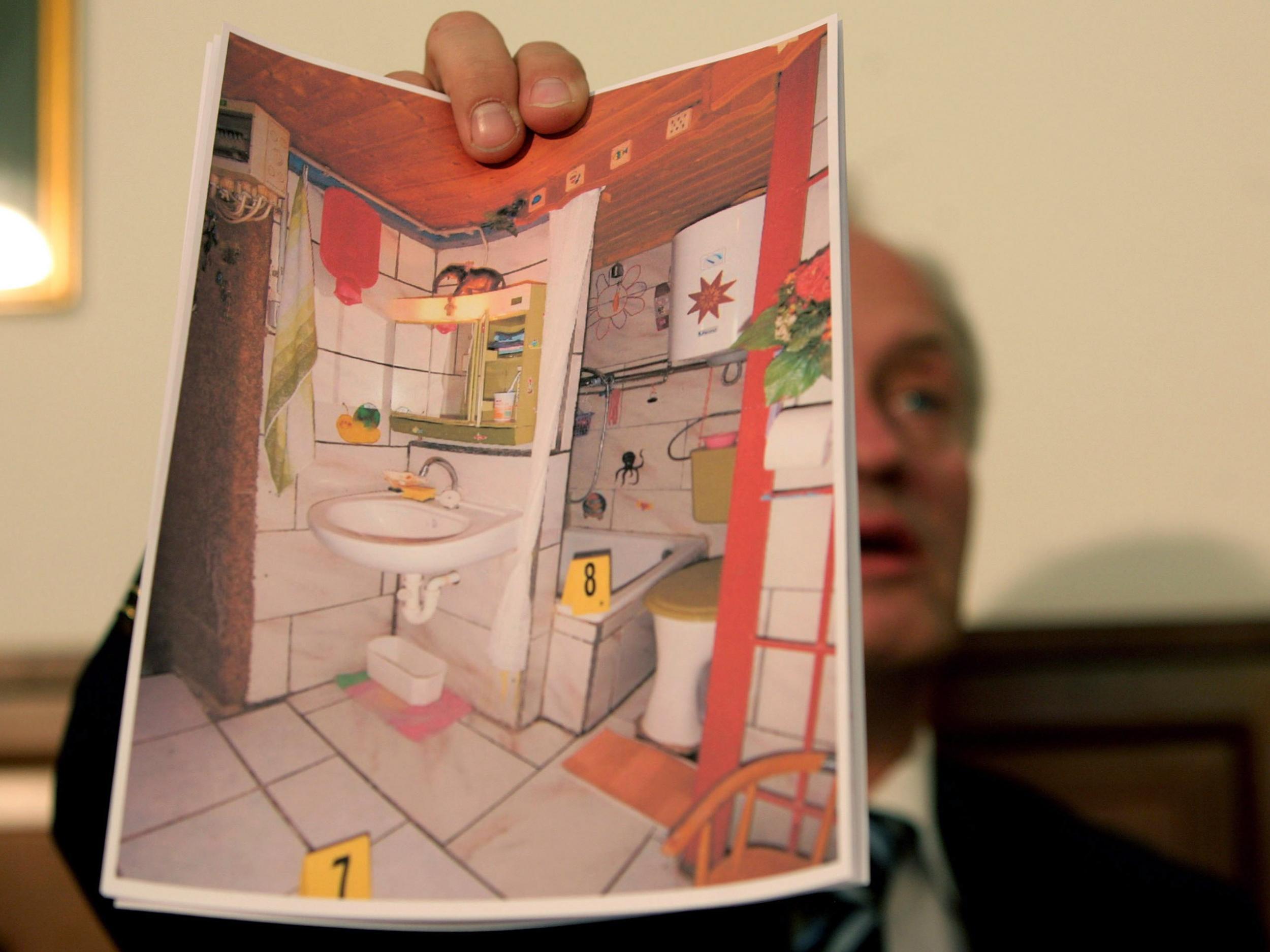 An investigator holds up a picture of the cellar where Fritzl imprisoned his daughter for 24 years