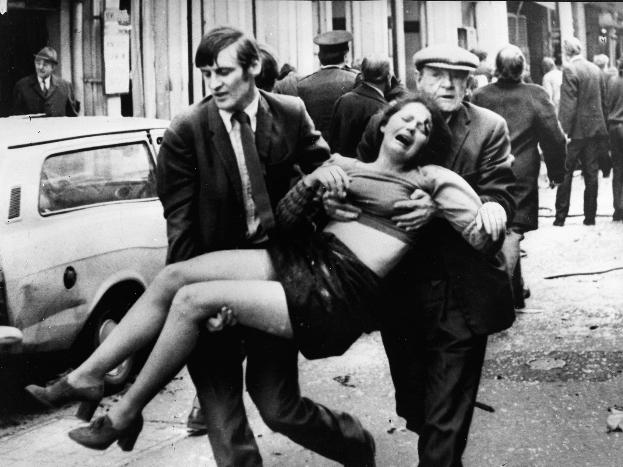 An injured girl is carried after a terrorist bomb exploded in a car parked in a busy shopping street in 1970s Belfast