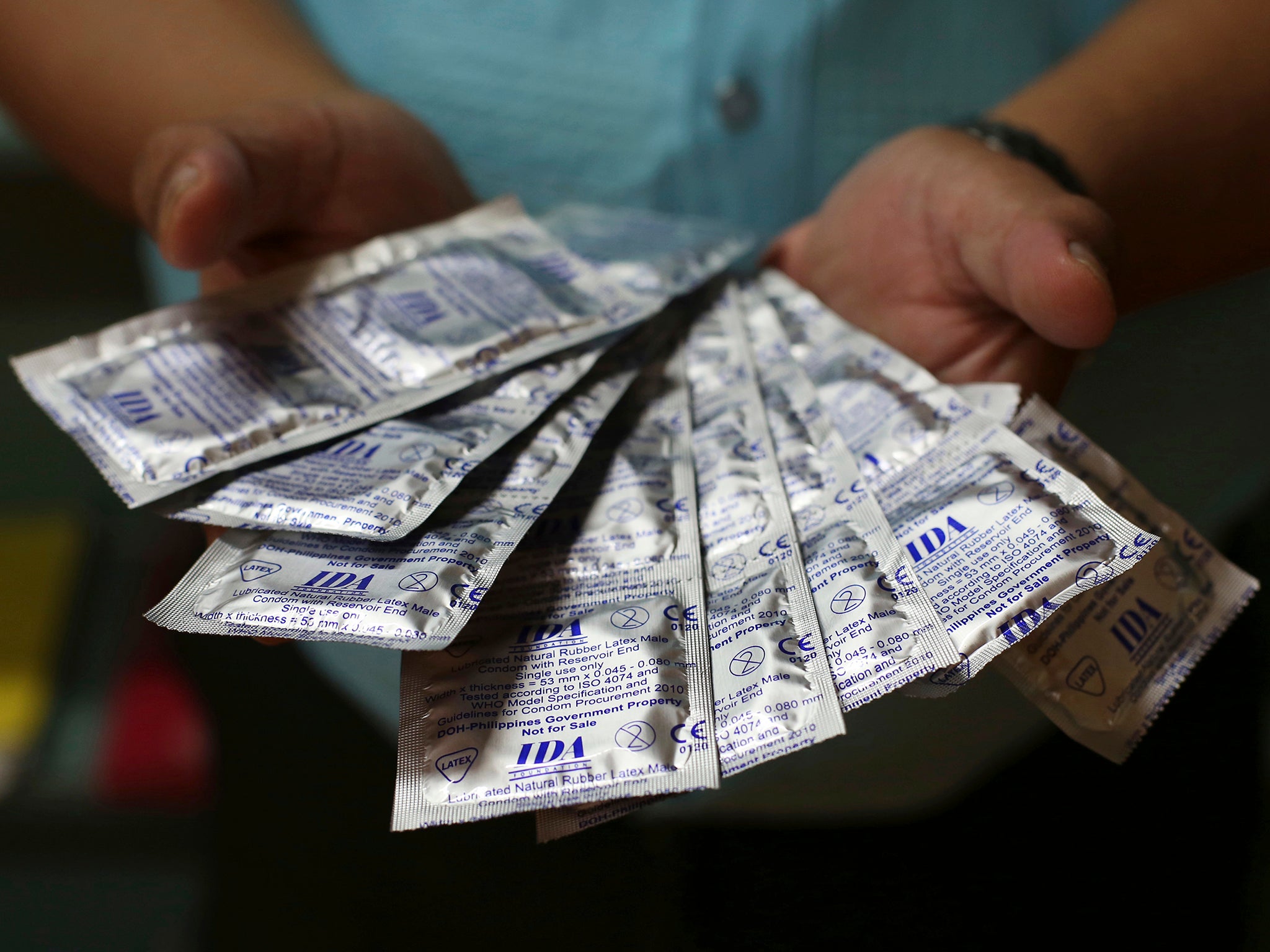 A Filipino health worker shows condoms that are given for free to the public by the Department of Health in Manila, Philippines