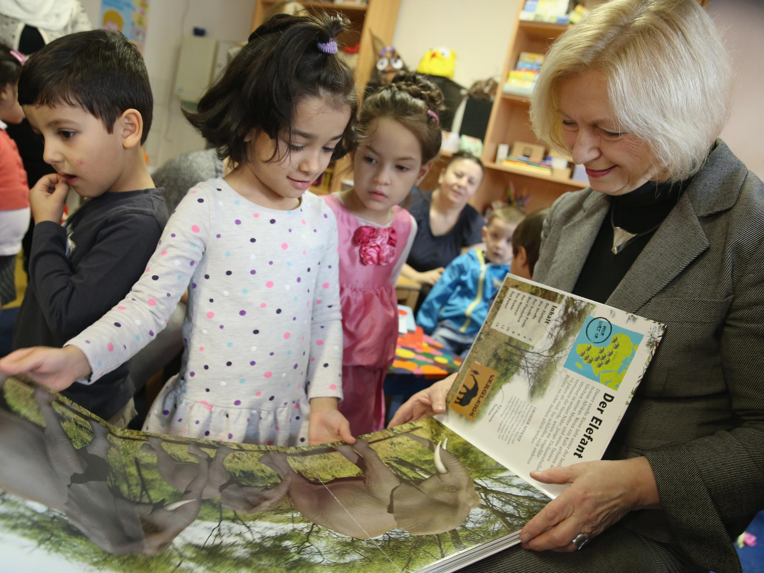 German Education Minister Johanna Wanka reads a book about animals with a 6-year-old girl from Afghanistan as part of a new initiative to help children of refugees