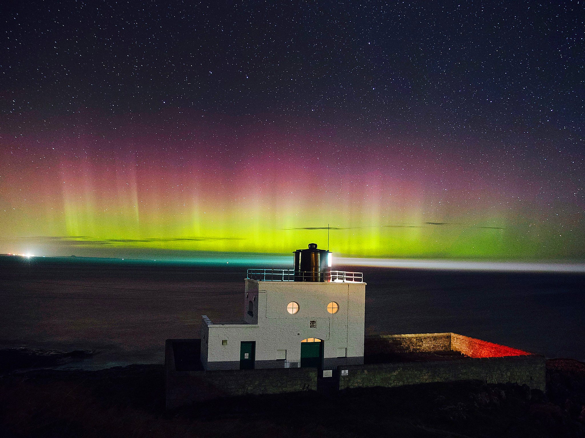 The Northern Lights appearing in the sky over Bamburgh lighthouse in Northumberland in December