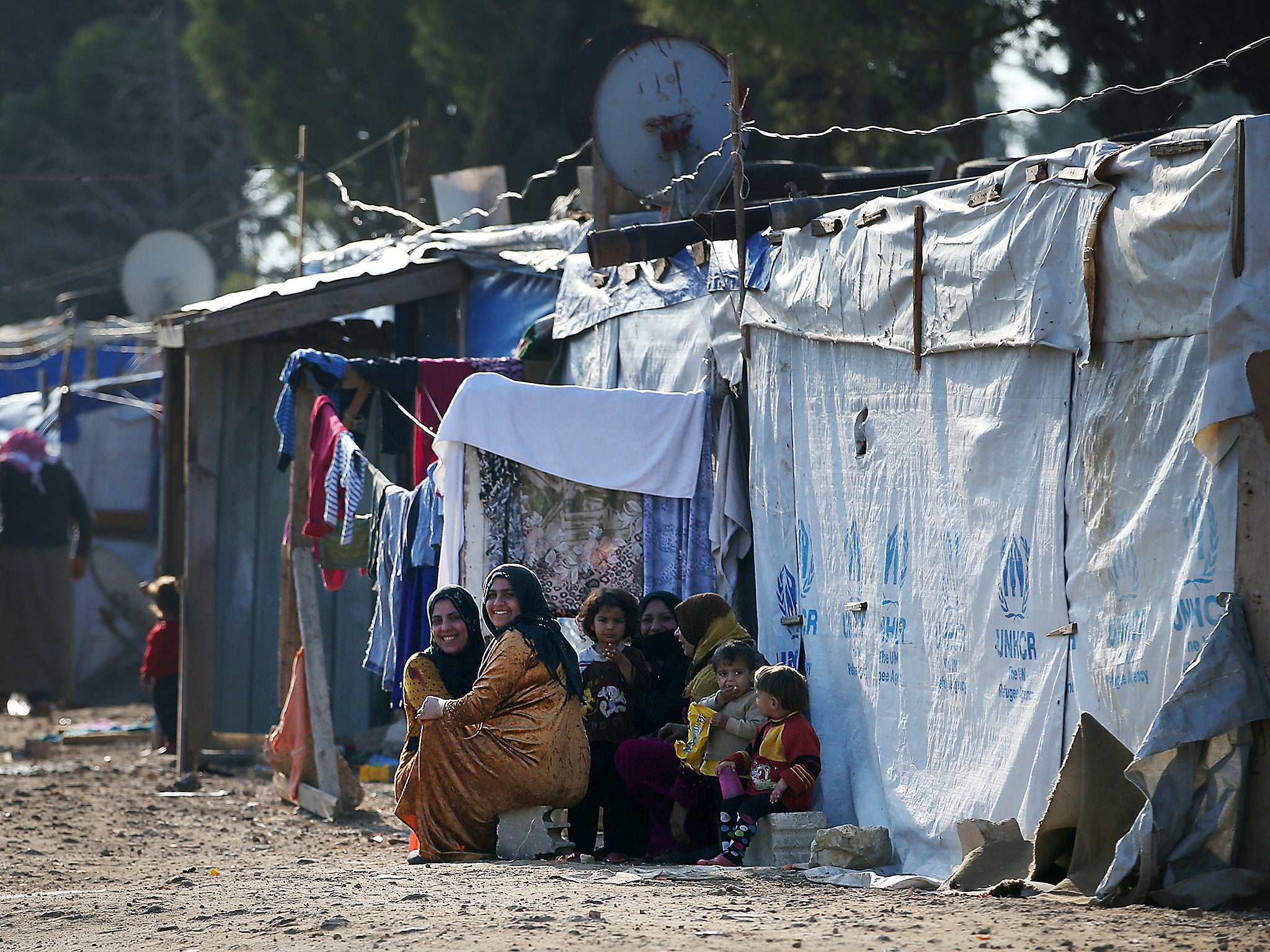 Syrian refugee women and children outside the entrance to their tents in the refugee camp in the Bekaa Valley, Lebanon