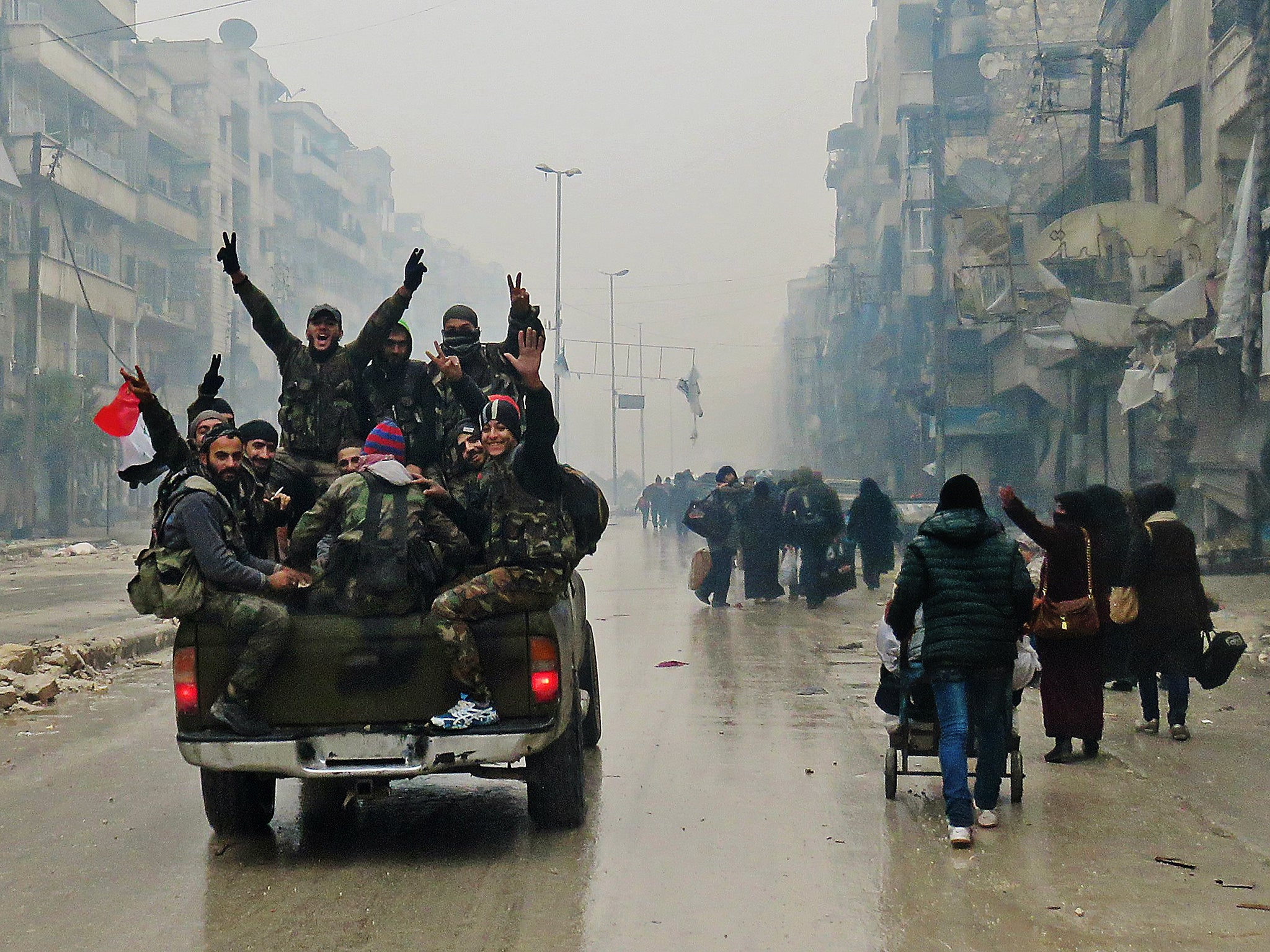 Syrian pro-regime fighters, gesture as they drive past resident fleeing violence in the restive Bustan al-Qasr neighbourhood, in Aleppo's Fardos neighbourhood