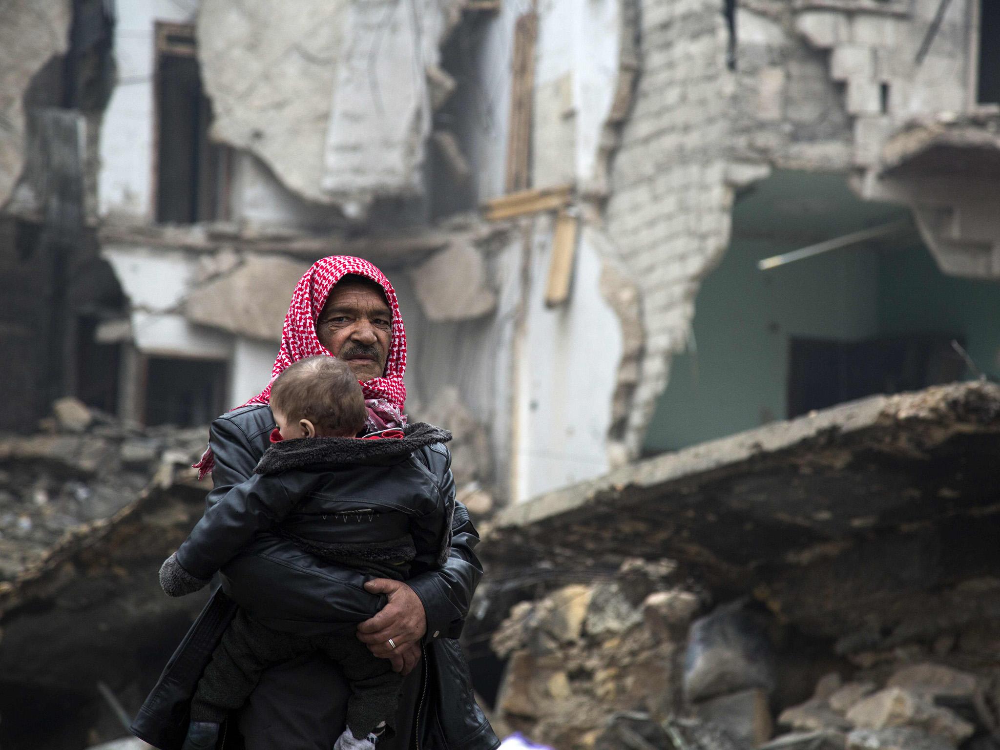 A man carries a child through the ruins of Aleppo in this file photo from December 2016. Estimates put the amount of the eastern half of the city destroyed by Syrian government and Russian bombing at 60 per cent