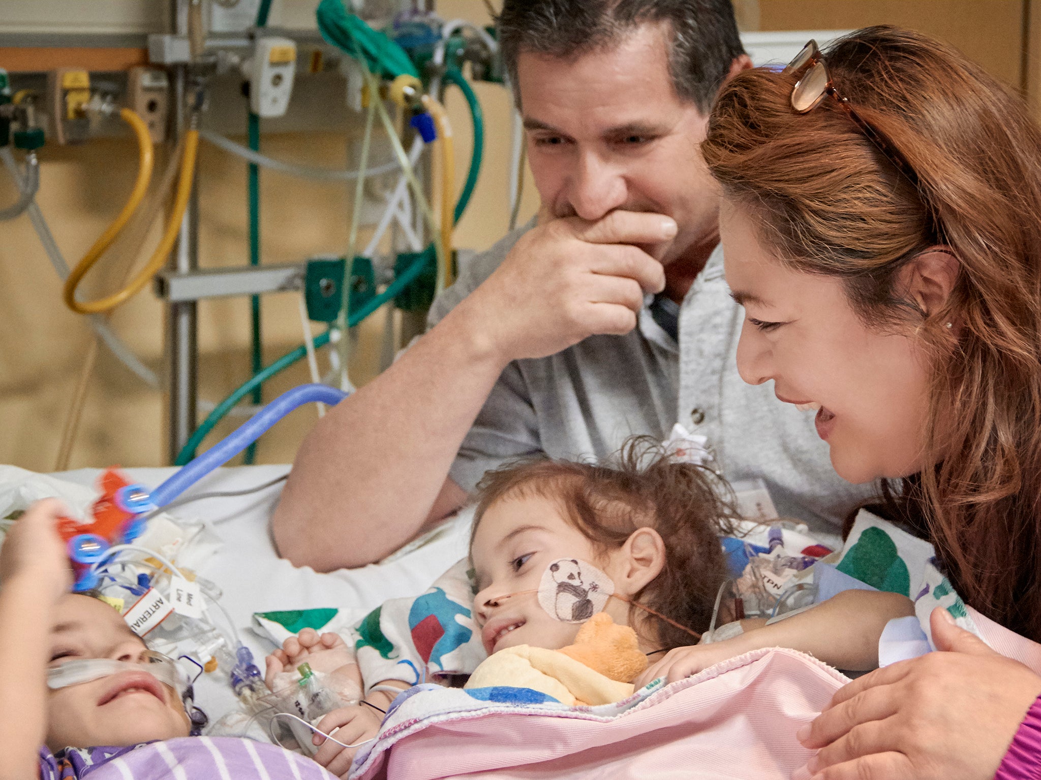 Formerly conjoined twin girls, Eva, left, and Erika, right, reunite for the first time since separation surgery with their parents, Arturo Sandoval and his wife, Aida, in Palo Alto, California