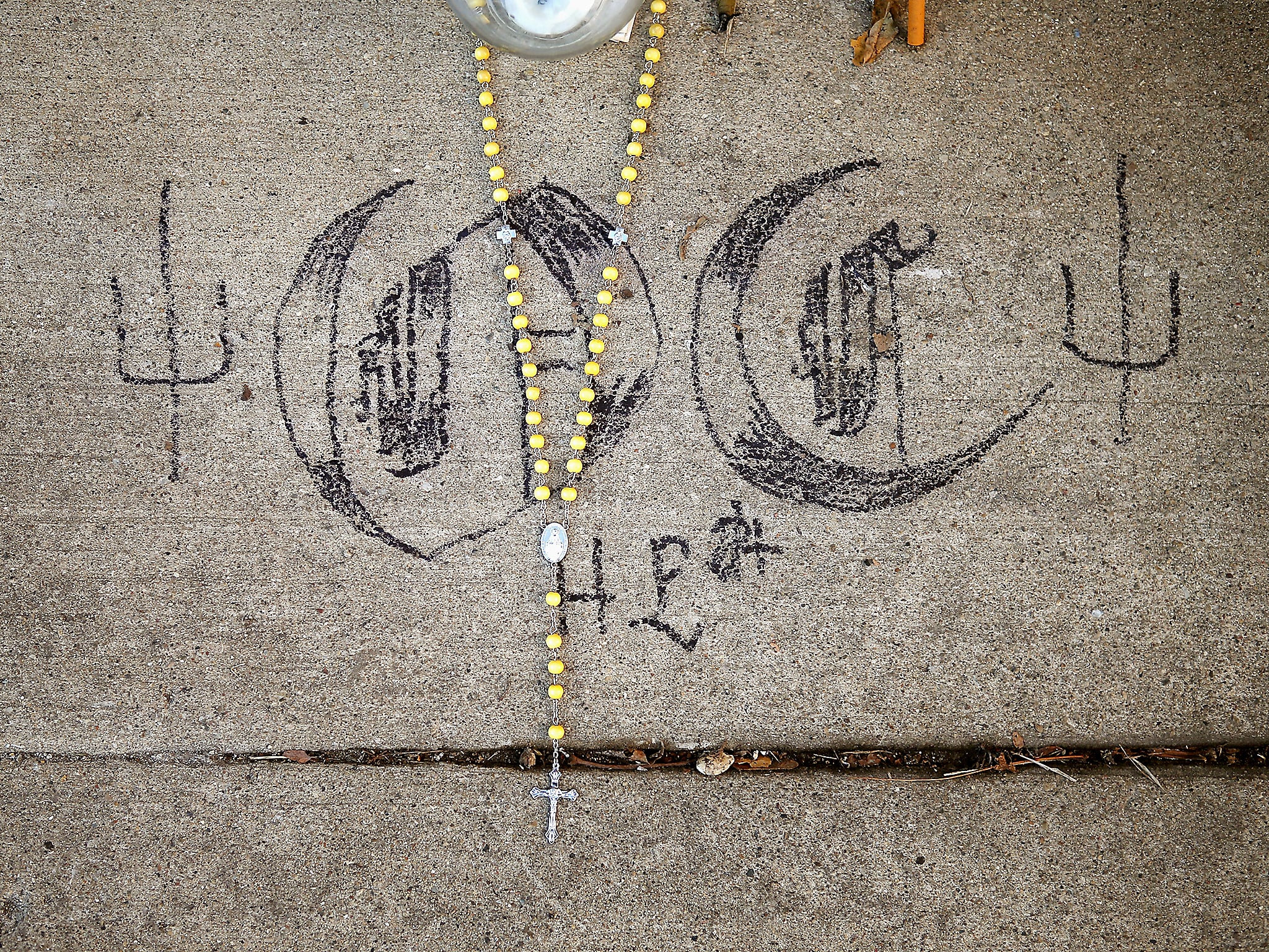 A rosary and gang symbols are part of a memorial created in an alley near the spot where 20-year-old Octavius Dontrell Lamb was shot and killed