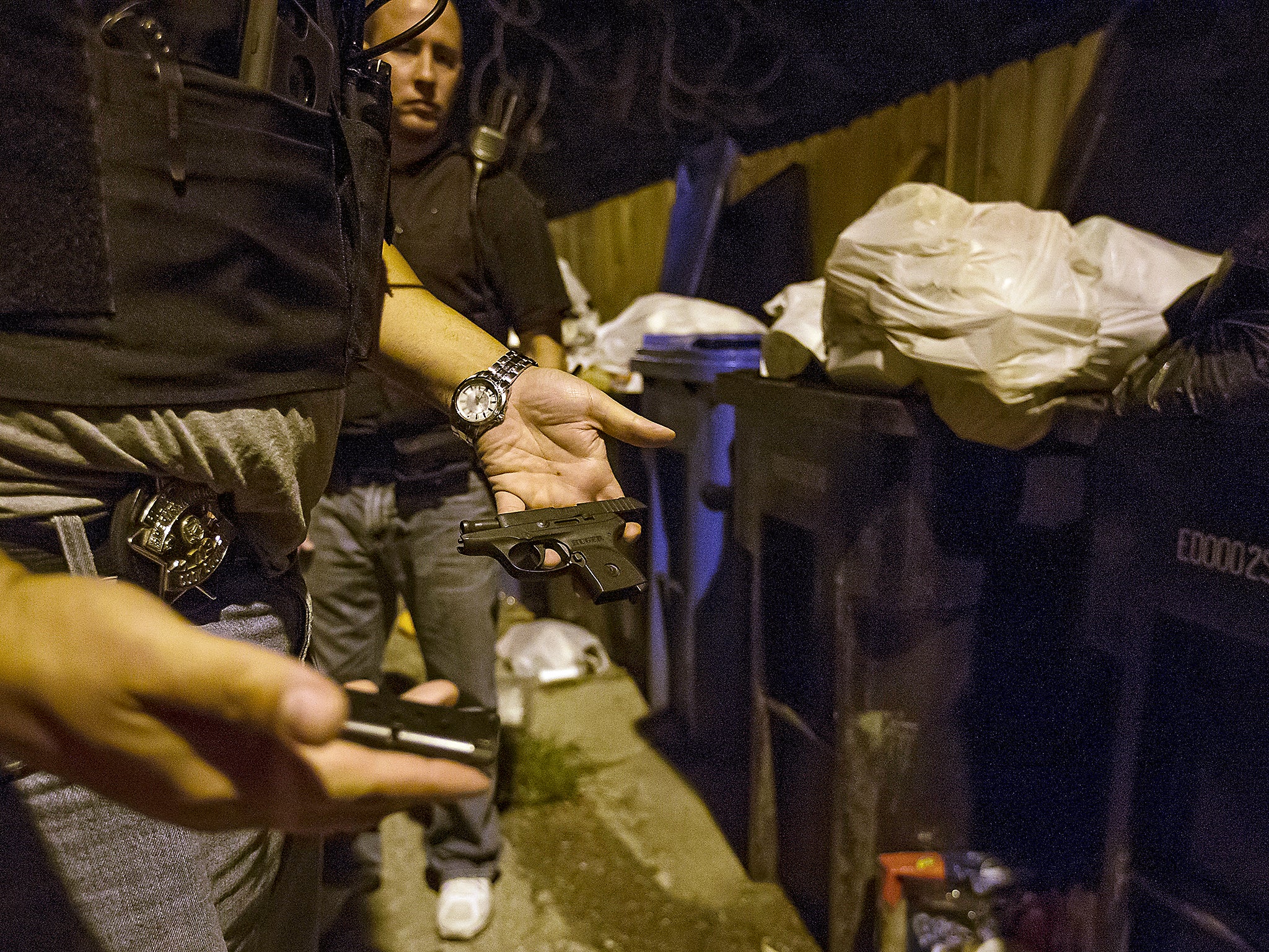 Cook County Sheriff police officers find a handgun hidden among the trash cans in an alley in the Austin neighborhood in Chicago, Illinois