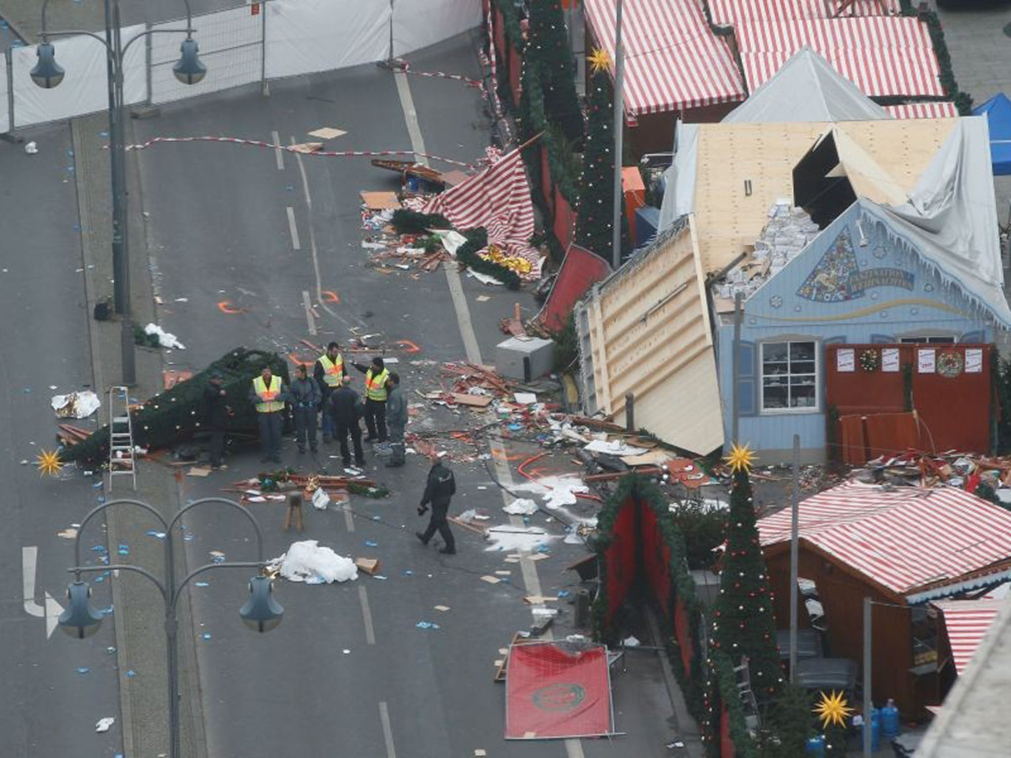 Policemen investigate the scene where a truck ploughed into a crowded Christmas market in the German capital last night in Berlin