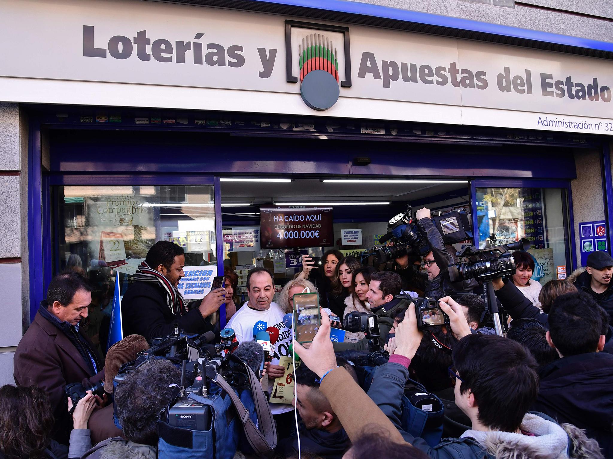 Spanish Administration Lottery owner Agustin (CL) answers to journalists as he celebrates having sold the first prize ticket (66513) of Spain's Christmas lottery named "El Gordo" (Fat One) in the Embajadores neighbourhood in Madrid