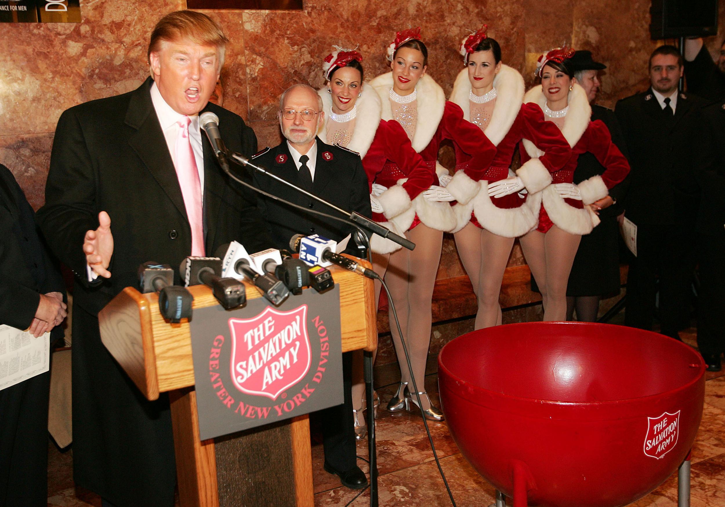 Members of the Radio City Rockettes listen to Donald Trump speaking at a Christmas ceremony in Trump Tower, New York 2004