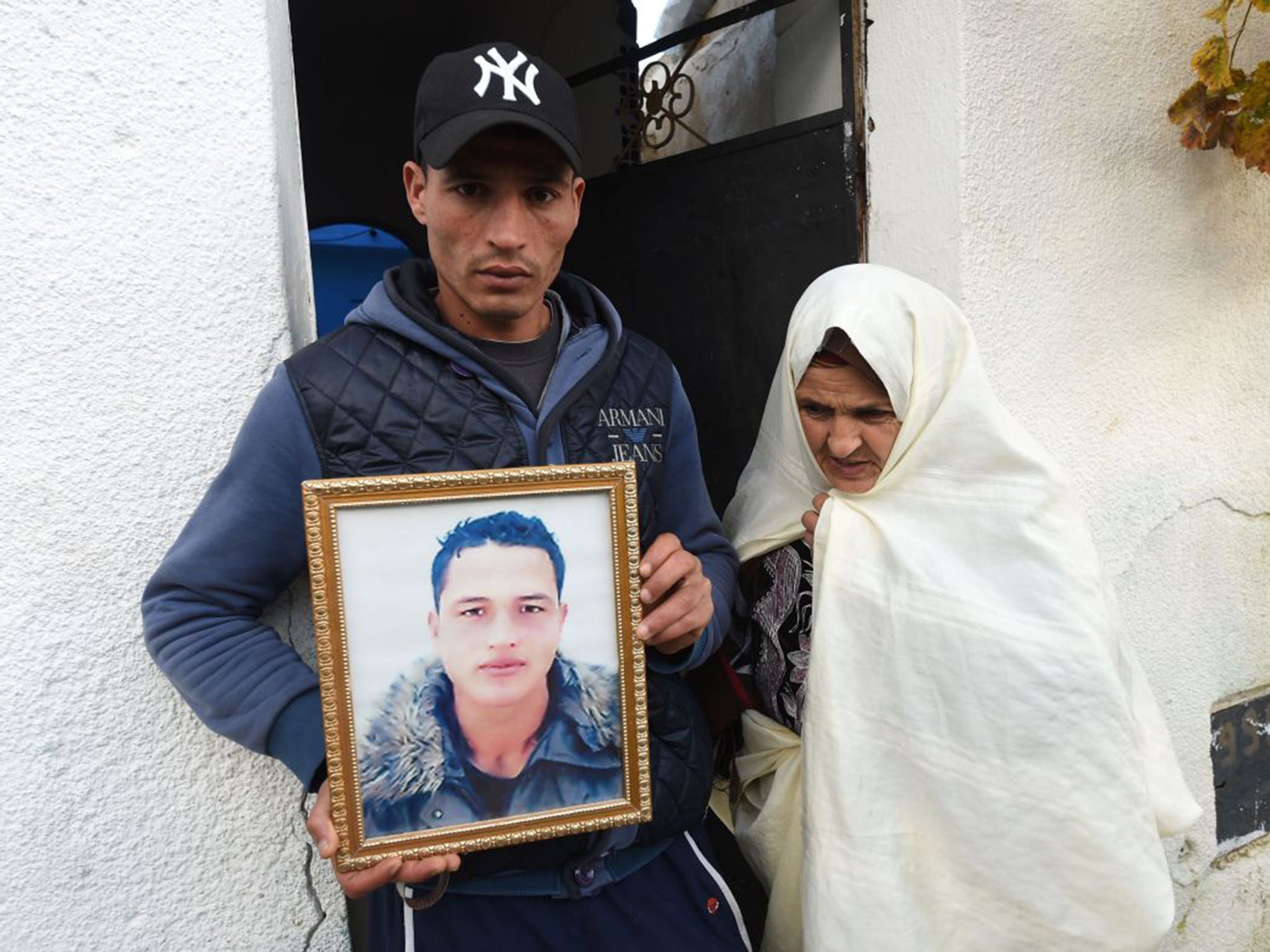 Walid Amri poses with a portrait of his brother of Anis outside the family house in the town of Oueslatia, Tunisia