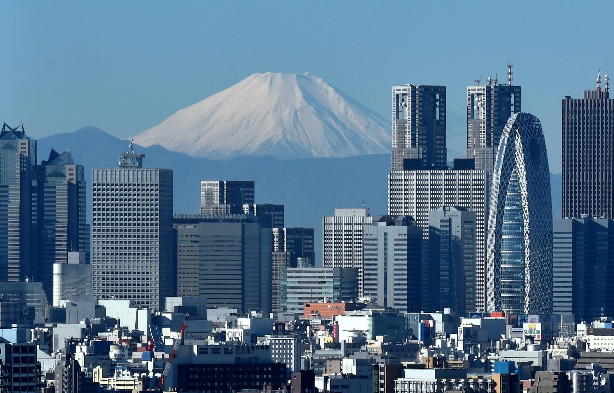 Japan's highest mountain, Mount Fuji (C) is seen behind the skyline of the Shinjuku area of Tokyo on December 6, 2014