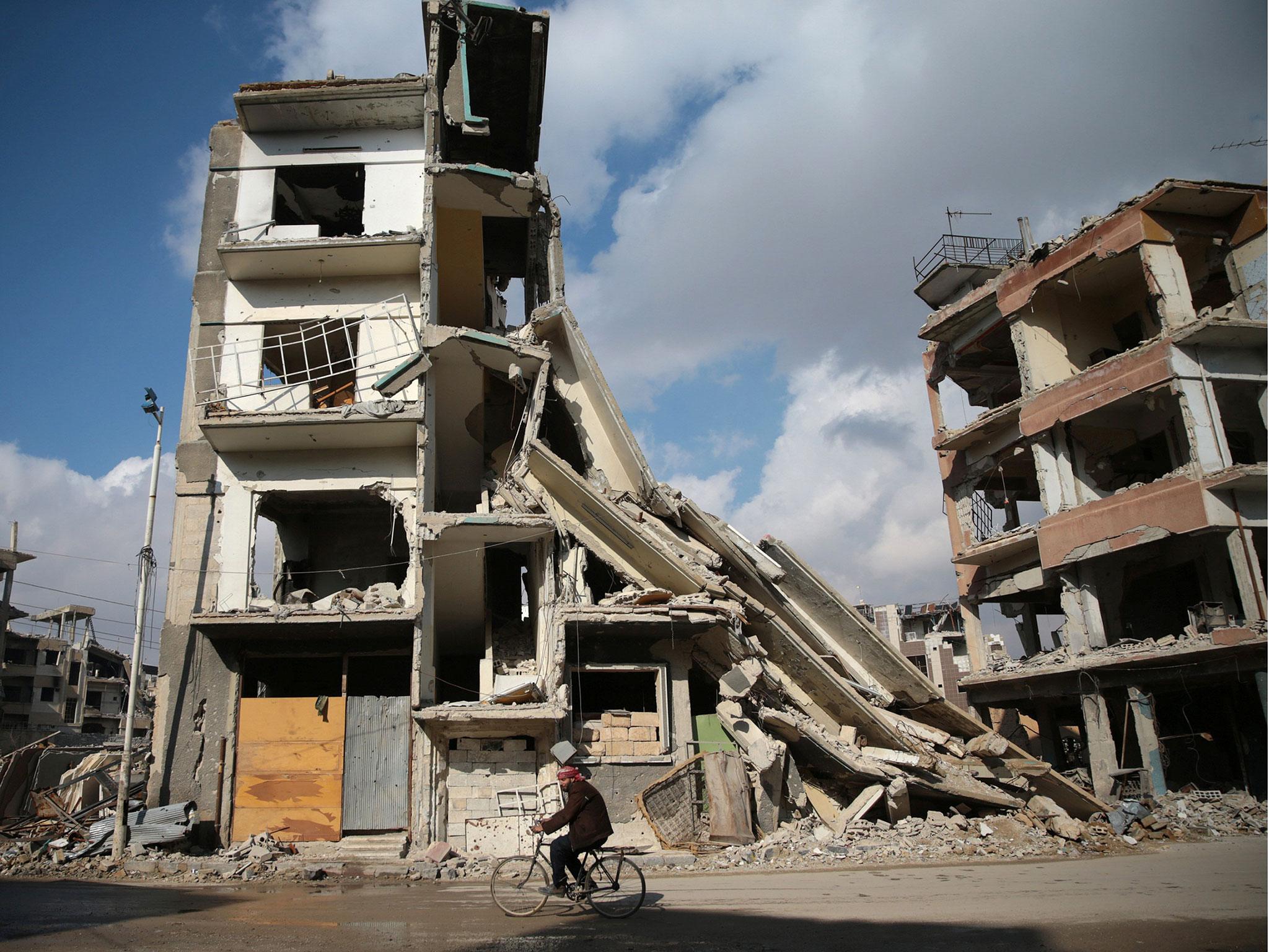 A man rides a bicycle near damaged buildings in the rebel held besieged city of Douma, in the eastern Damascus suburb of Ghouta, Syria, 30 December, 2016