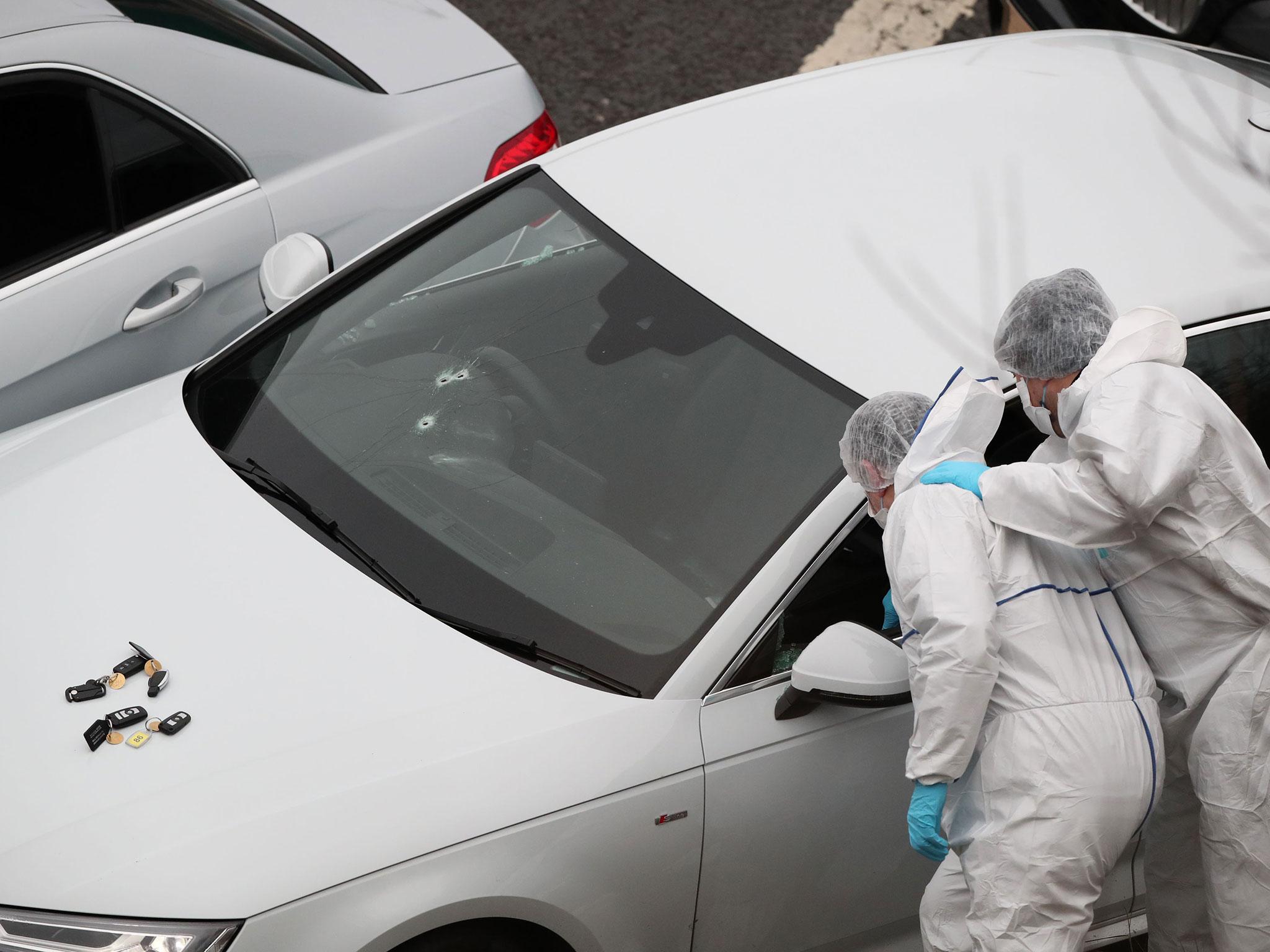 Police forensics officers examine a silver Audi with bullet holes in its windscreen at the scene near junction J24 of the M62 in Huddersfield (PA )