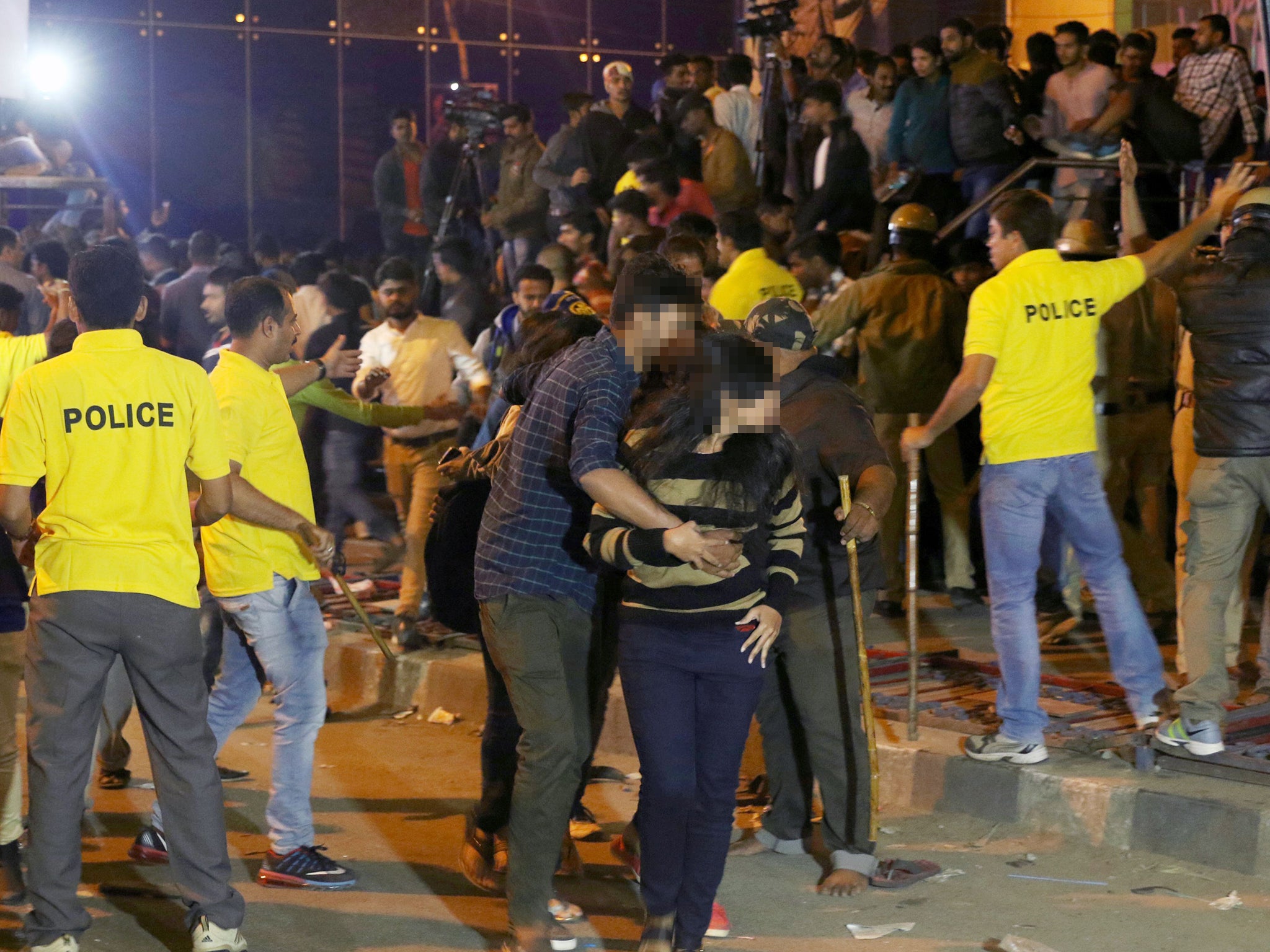 A man helps a woman leave as police try to manage crowds during New Year's Eve celebrations in Bangalore