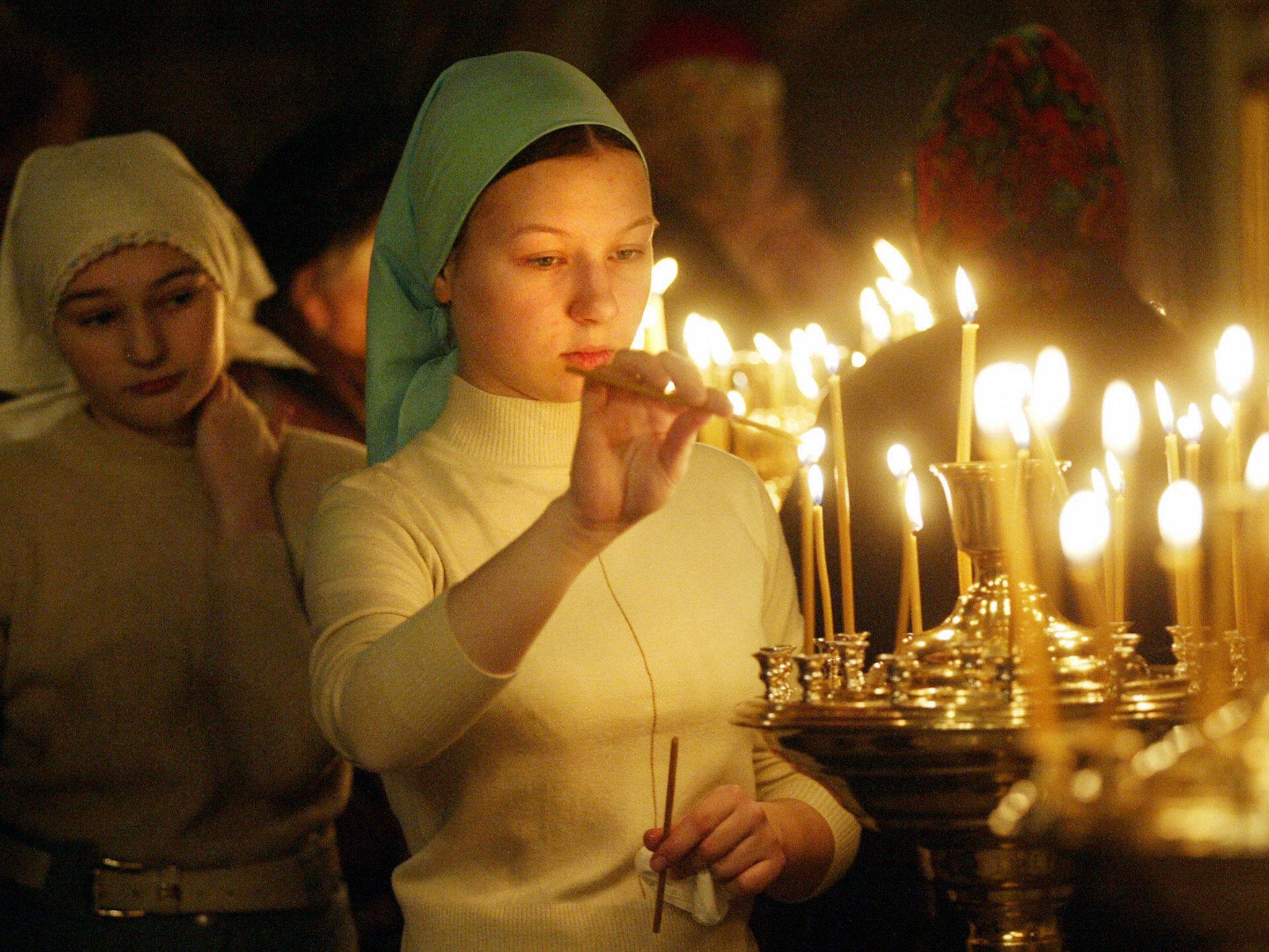 Russian believer lights a candle during the Christmas Eve religious service in a church in Kolomenskoye