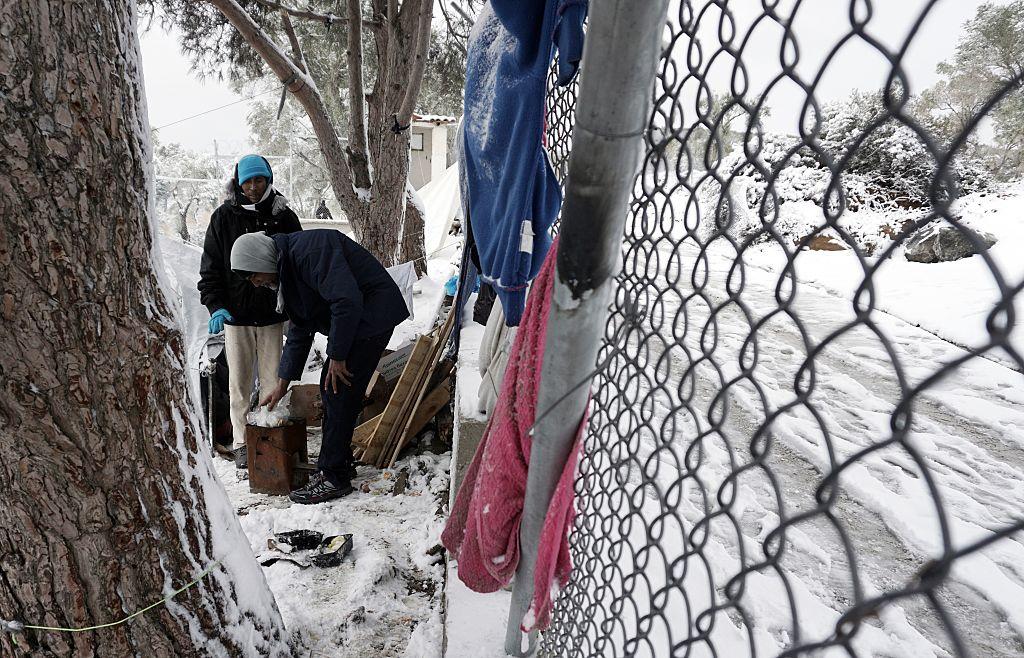 Women try to light a fire at the Moria refugee camp on the island of Lesbos following heavy snow on 7 January (AFP/Getty)