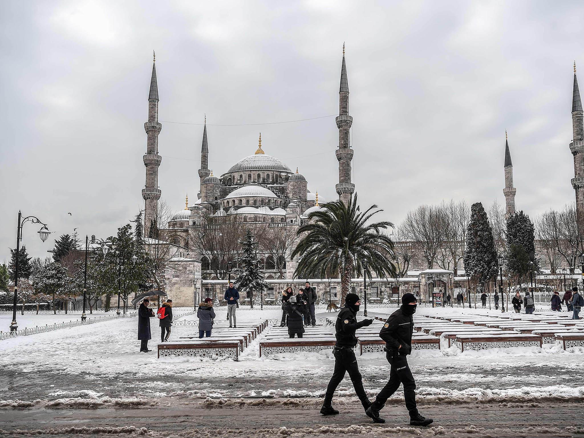 Snowfall offers a moment of peace, as anti-riot police officers patrol around the Blue mosque (Sultan Ahmet)