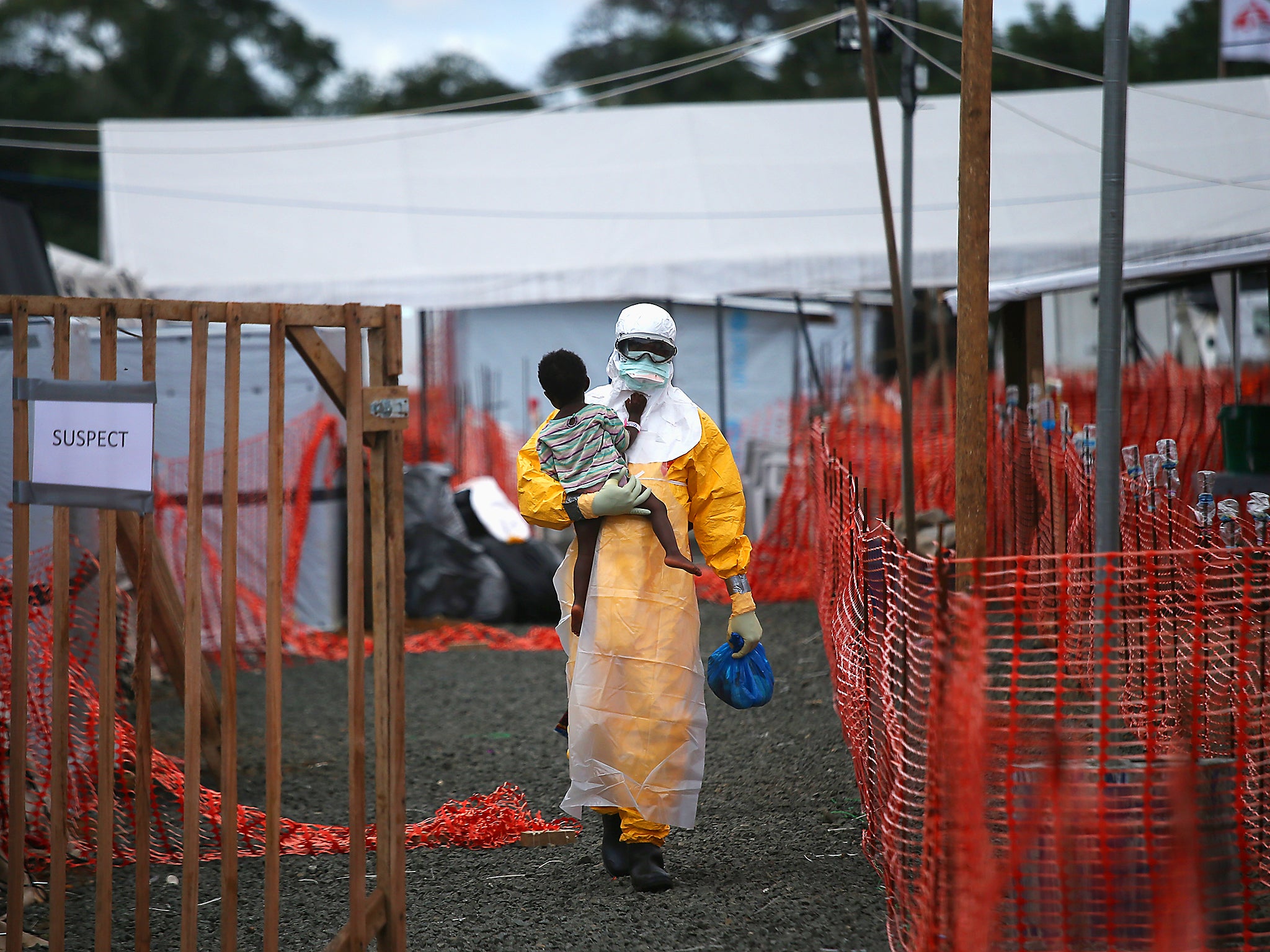 A Doctors Without Borders (MSF) health worker in protective clothing carries a child suspected of having Ebola in the treatment centre in Paynesville, Liberia