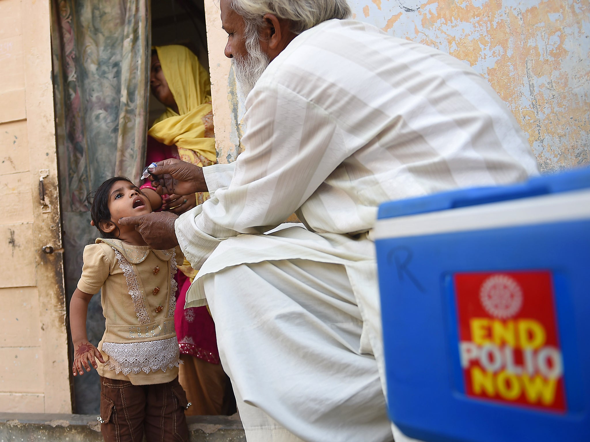 A Pakistani health worker administers polio vaccine drops to a child during a door-to-door polio campaign in Karachi