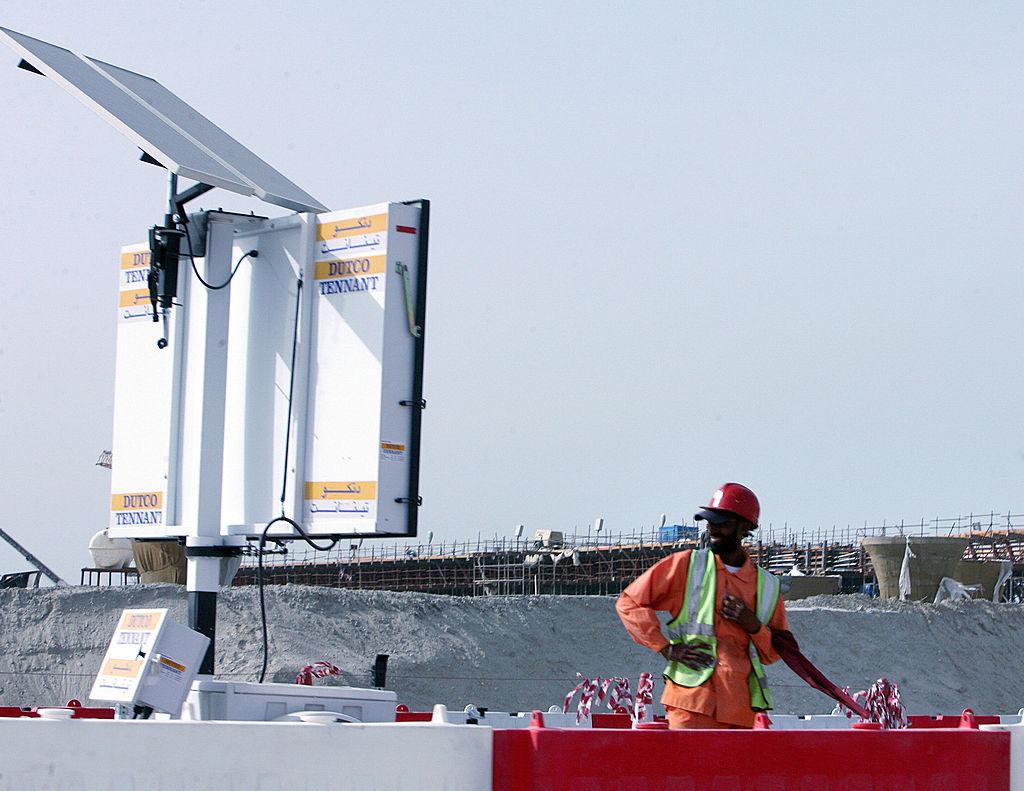 A construction worker stands beside a solar panel in Dubai, United Arab Emirates, on 16 April 2007