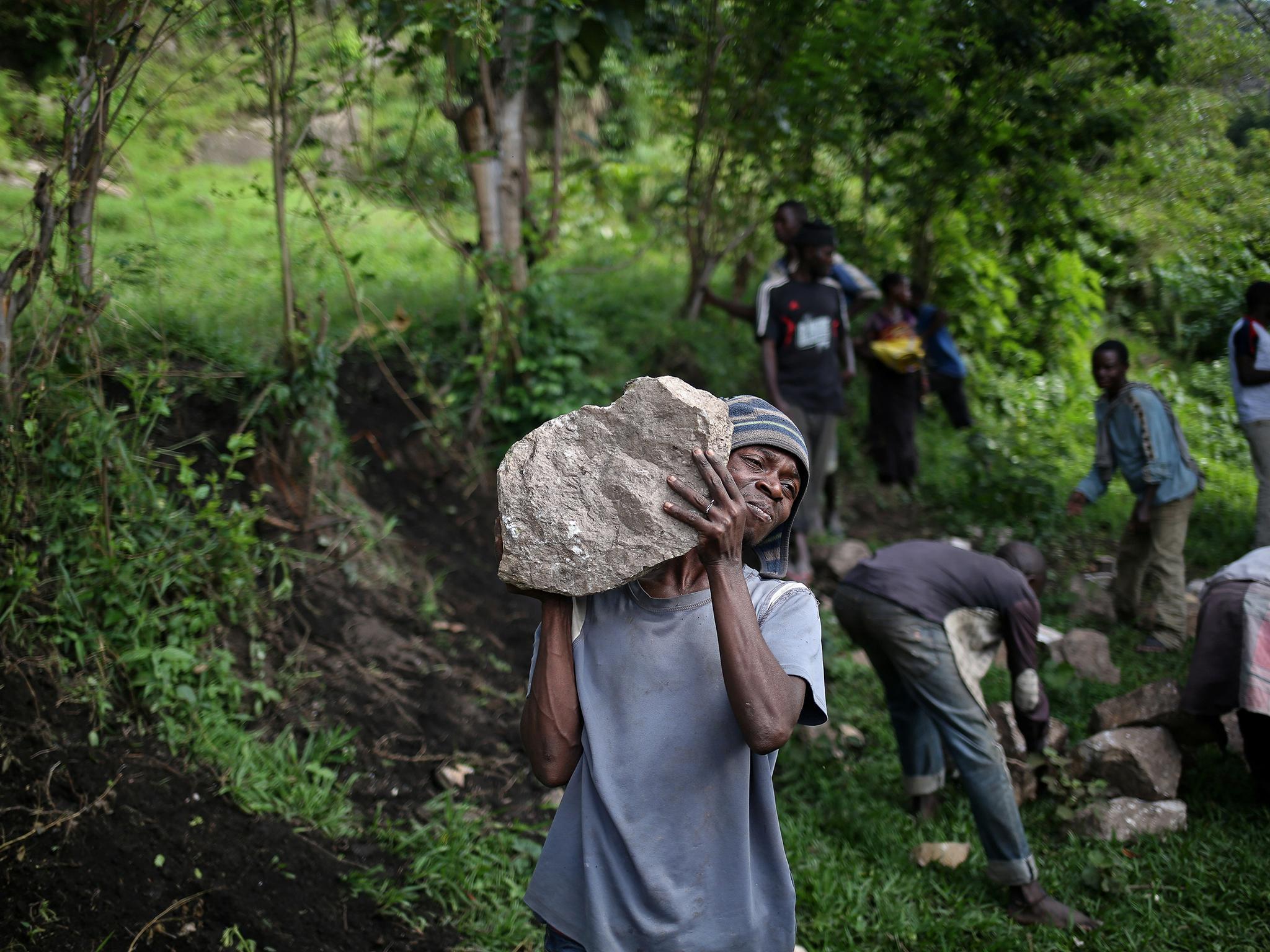 Ahadi, 23, carries heavy stones intended for the construction of an hotel in a village near the camp