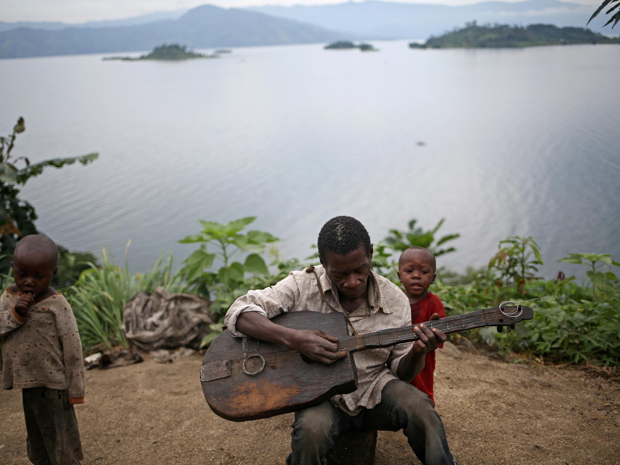 Mwenyezi, 36, plays a guitar at Kagorwa Pygmy camp on Idjwi island in the Democratic Republic of Congo